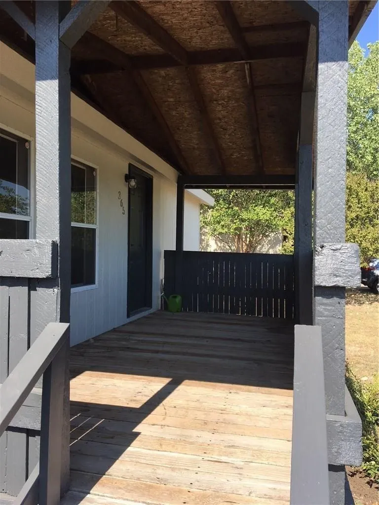 Covered wooden porch with dark-painted railings and support beams