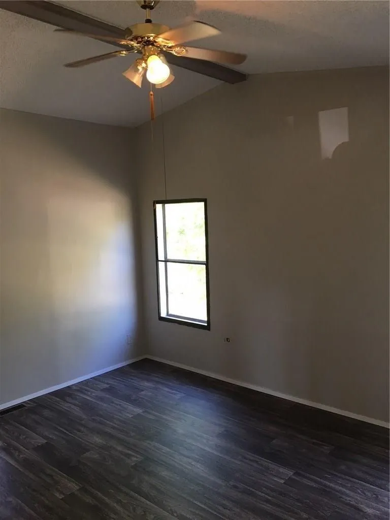 Wood-finish flooring, single window, sloped ceiling, and ceiling fan with integrated lighting