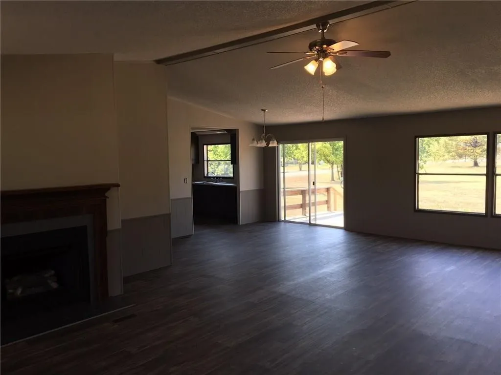 Spacious living area featuring wood-finish flooring, a decorative fireplace, and sliding glass doors