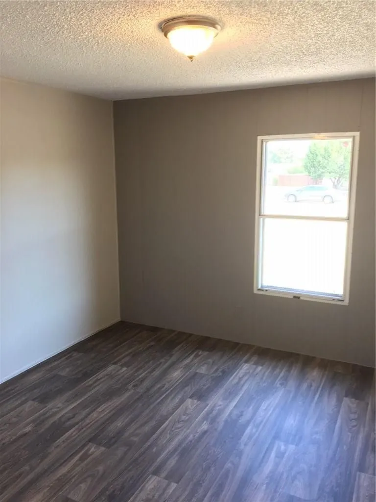 Wood-finish flooring with varying tones, neutral wall finishes, and a flush-mount ceiling light fixture