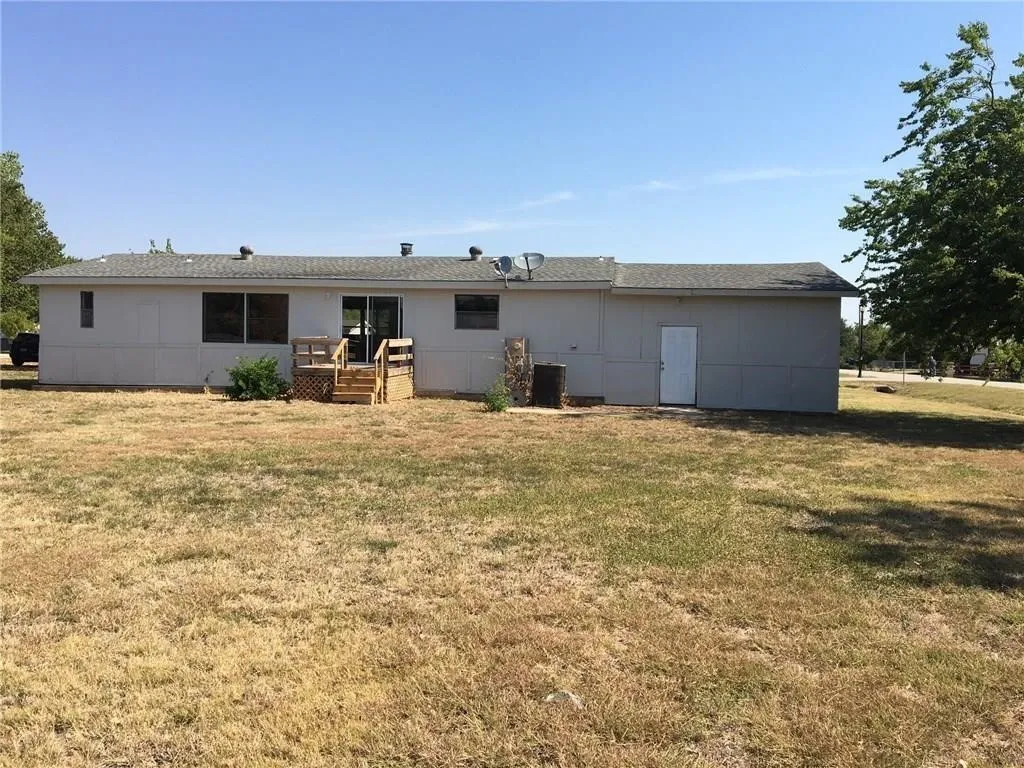 Rear exterior with a wooden deck, sliding glass doors, multiple windows, and a side entry door