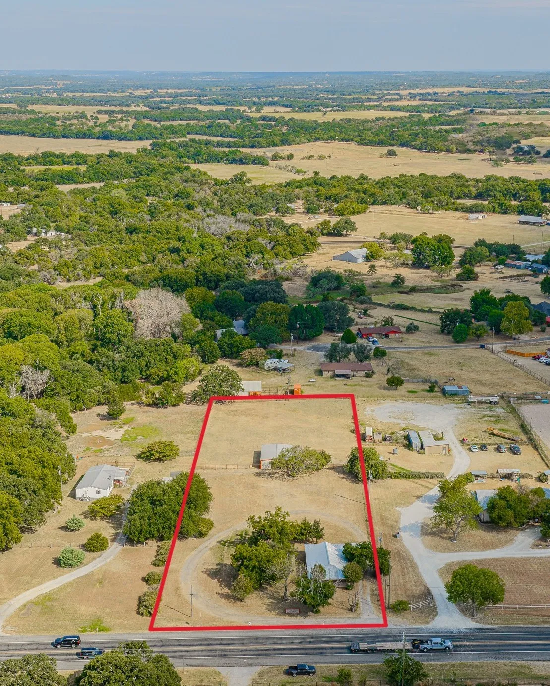 Expansive lot featuring two residential structures, a large undeveloped grassy area, and mature trees