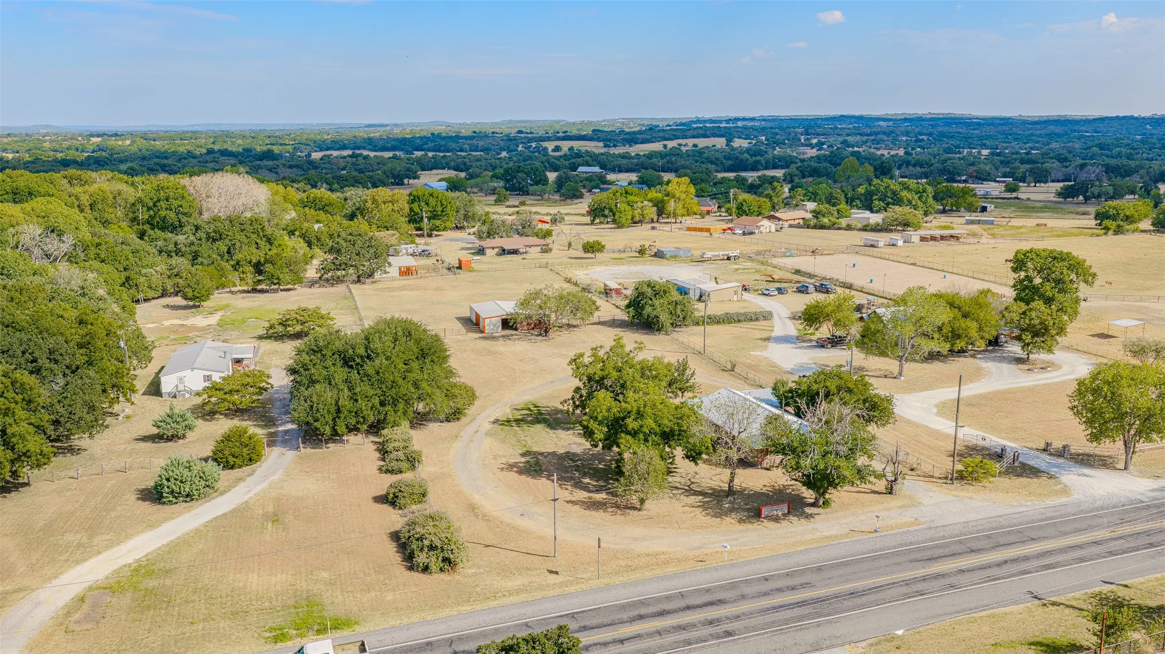 Expansive rural property featuring multiple structures, mature trees, and a paved road​​‌​​​​‌​​‌‌​‌‌​​​‌‌​‌​‌​‌​​​‌​​ frontage