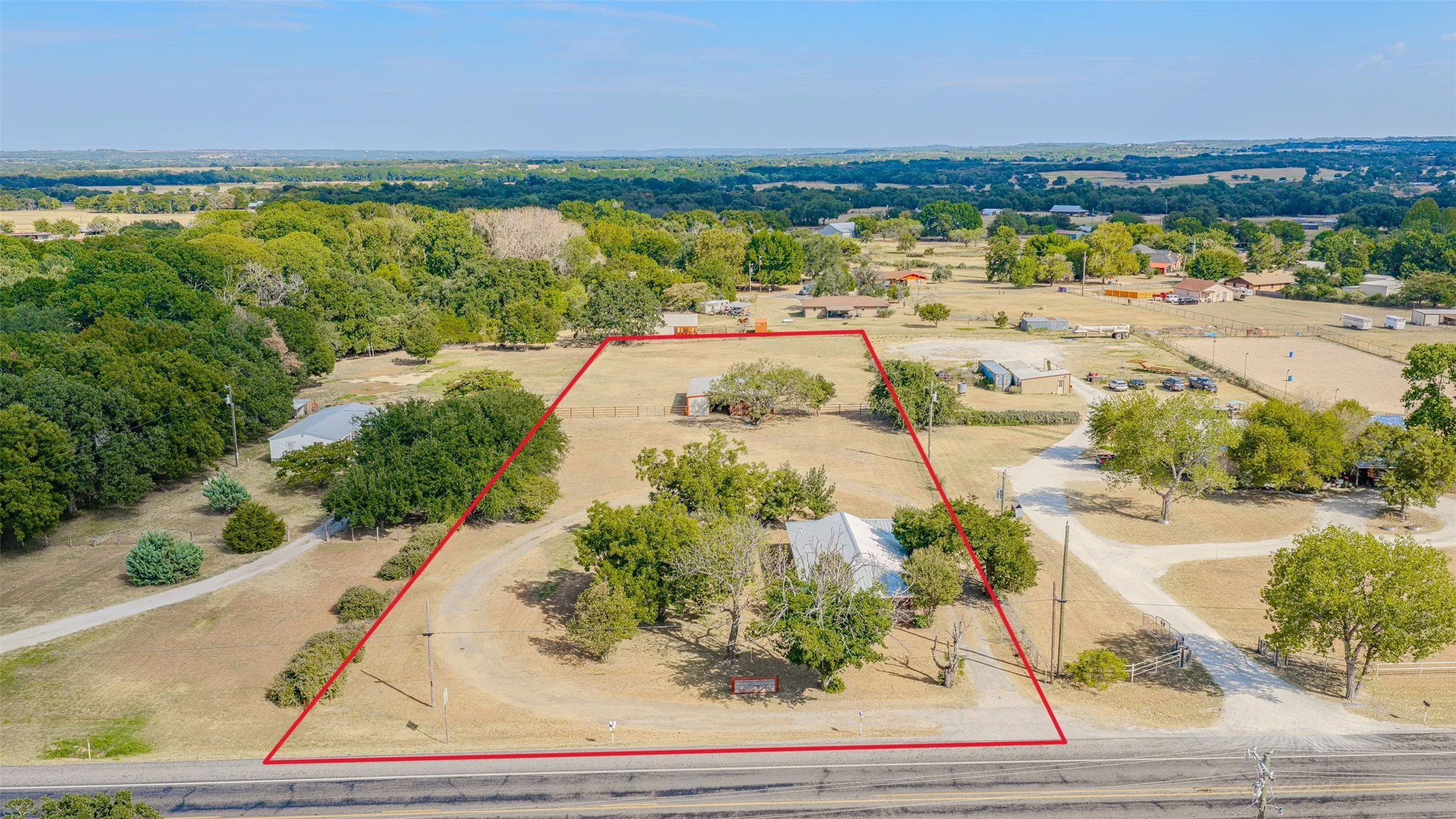 Expansive lot featuring mature trees, a gravel driveway, and a large metal outbuilding