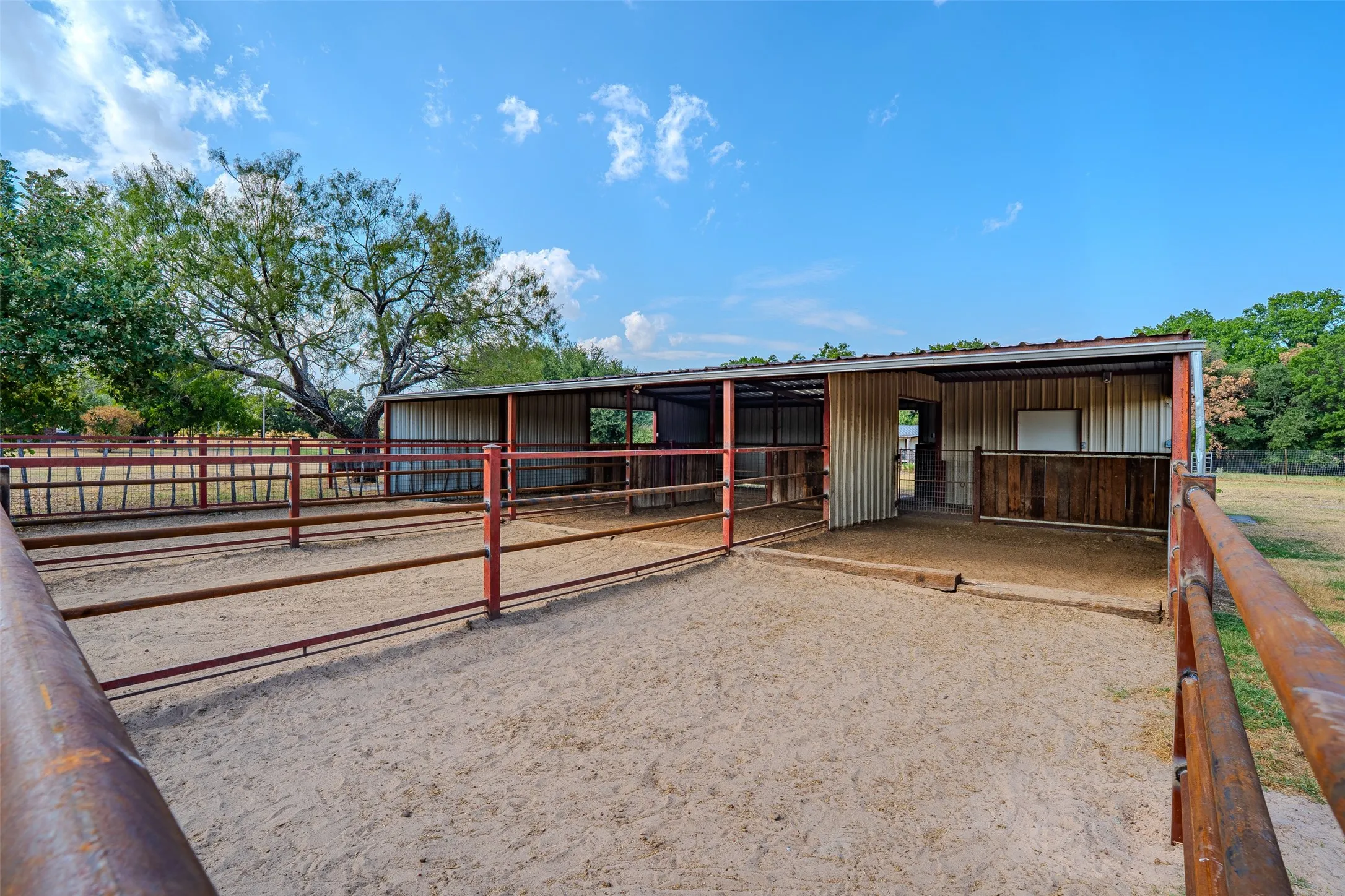Metal-roofed barn structure with multiple stalls, corrugated metal siding, and wood-paneled accents