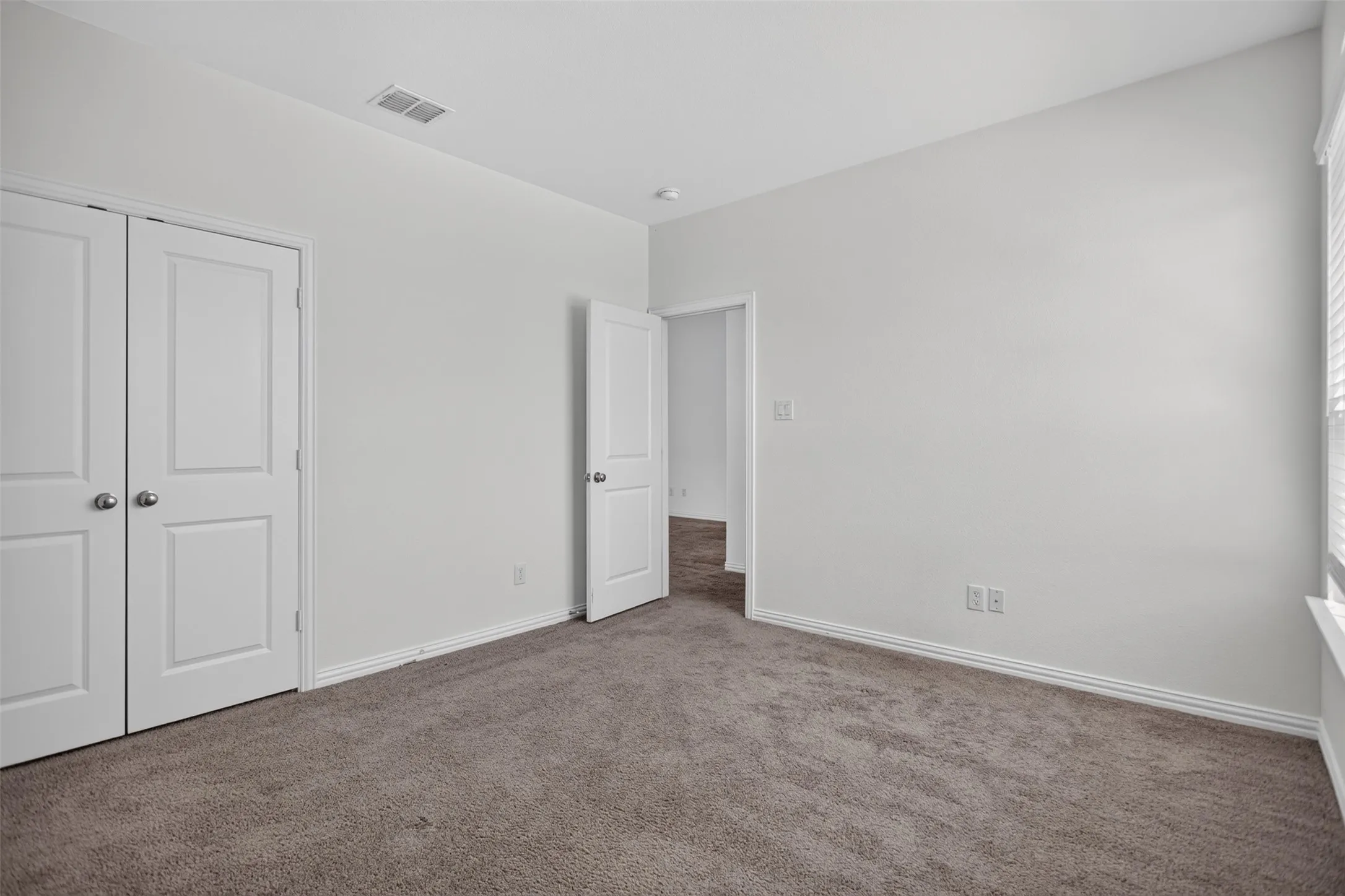 Plush carpet flooring, neutral paint color, white trim, and a white interior door