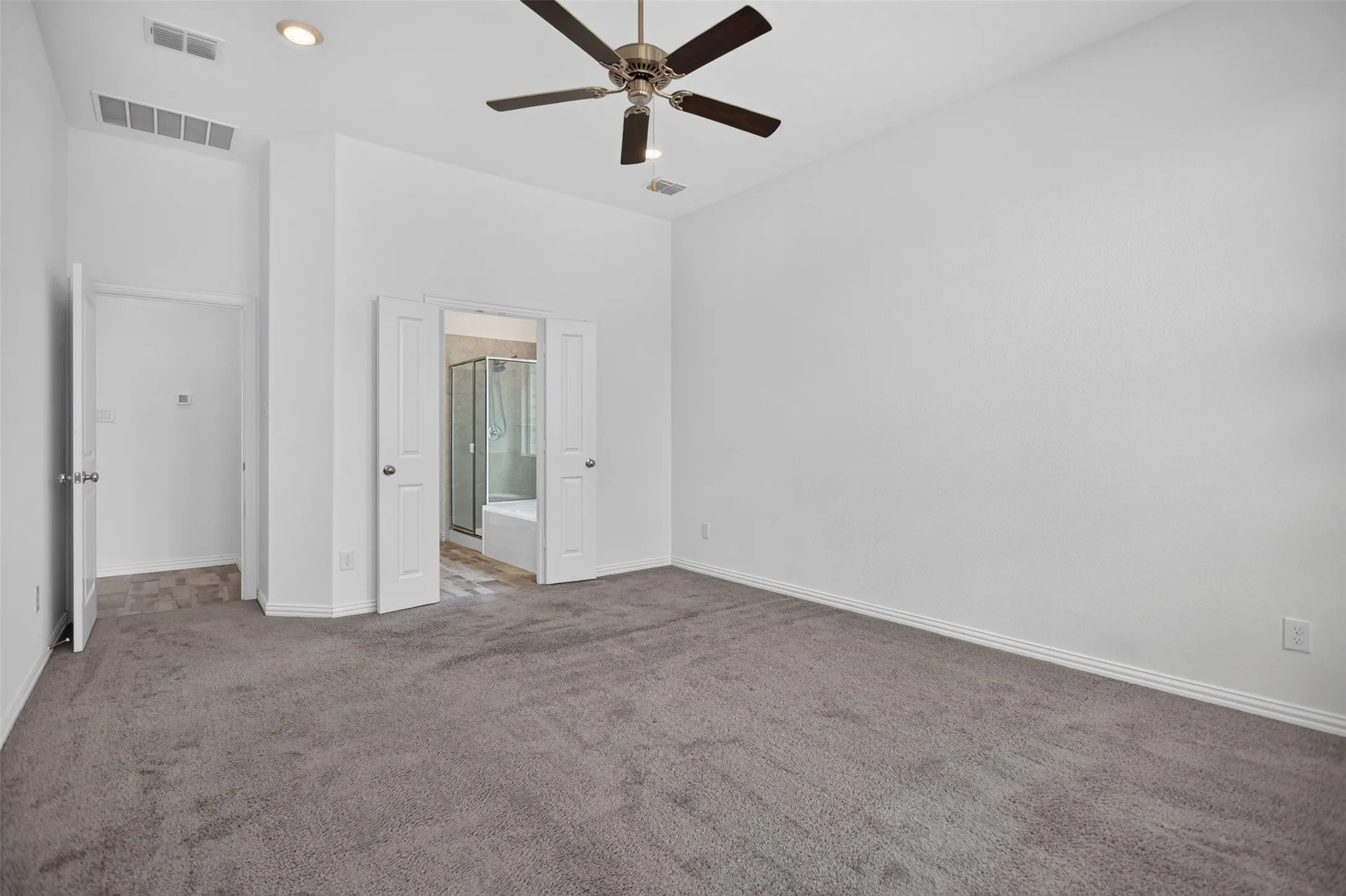 Carpeted flooring, ceiling fan with light fixture, recessed lighting, white interior doors, and a bathroom with a shower and tub combination