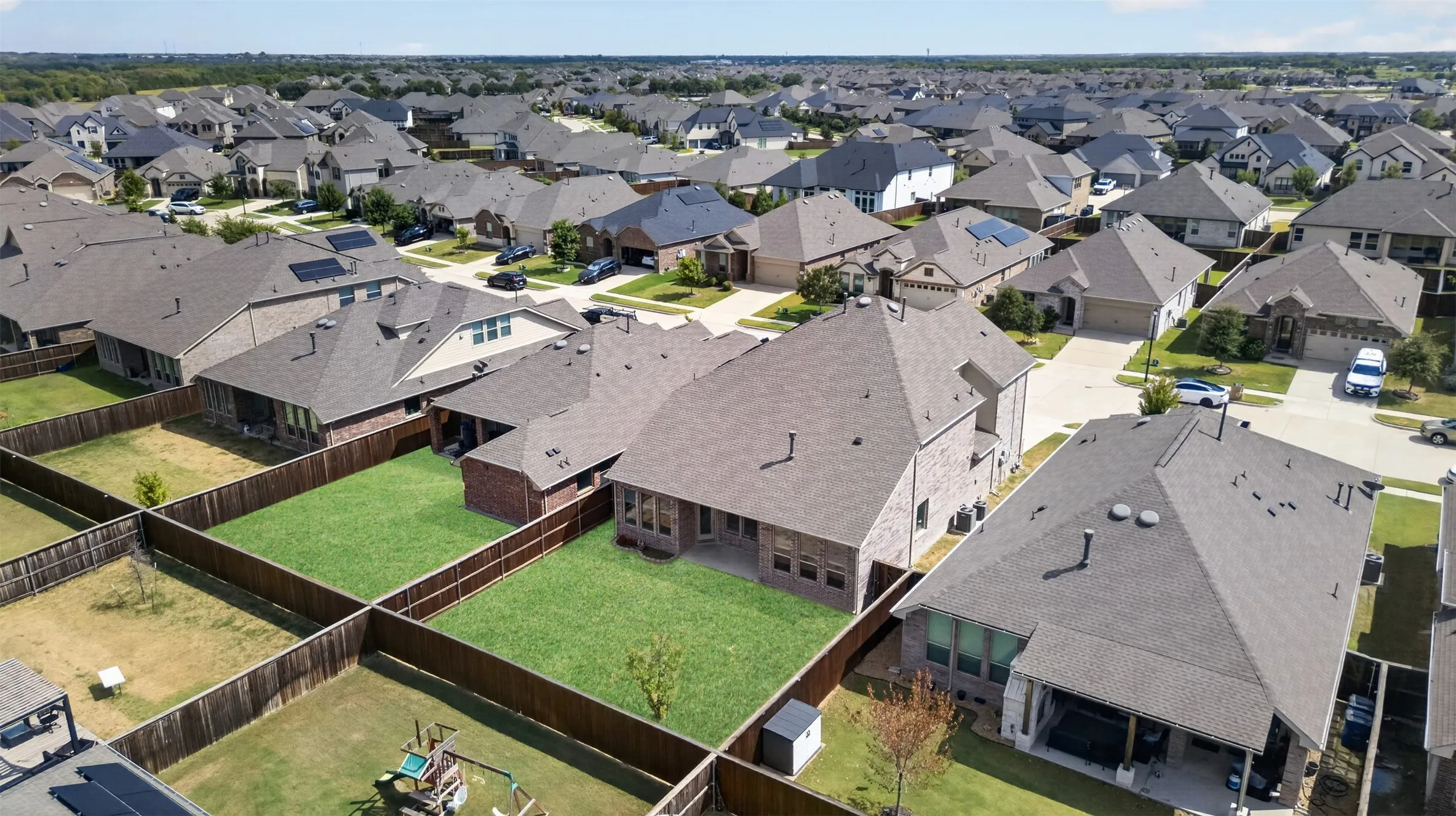 Expansive neighborhood with pitched roofs, brick exteriors, and private fenced backyards