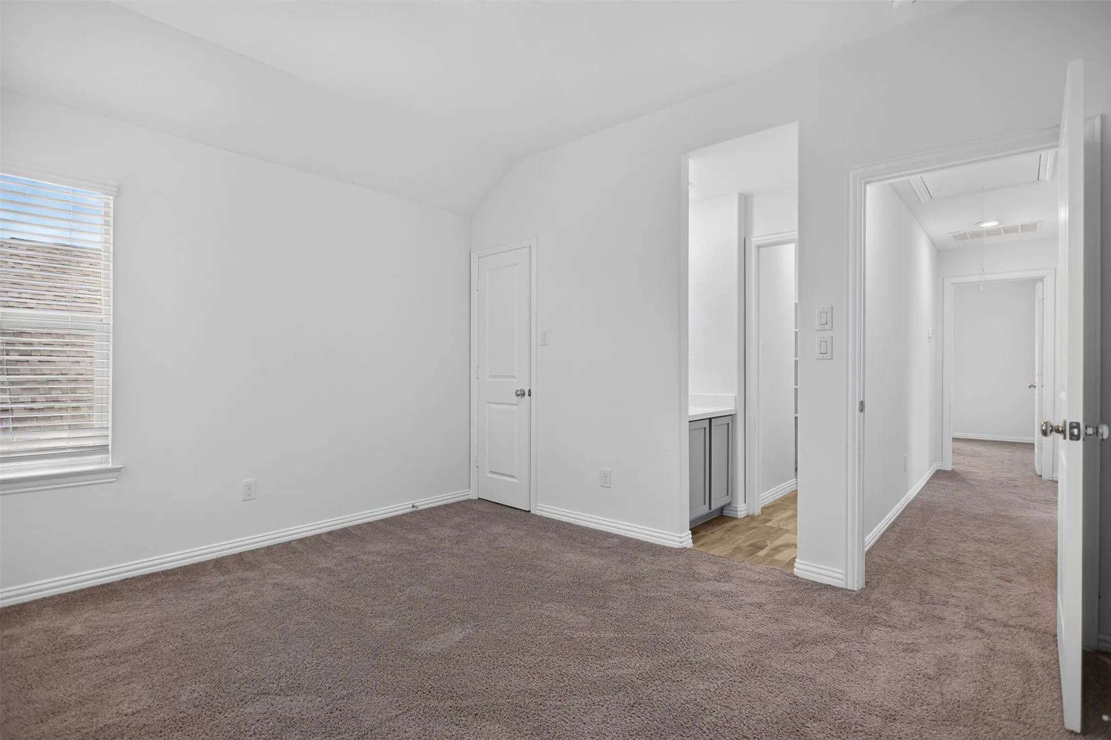 Vaulted ceiling, window with blinds, gray carpet, white trim, and white walls