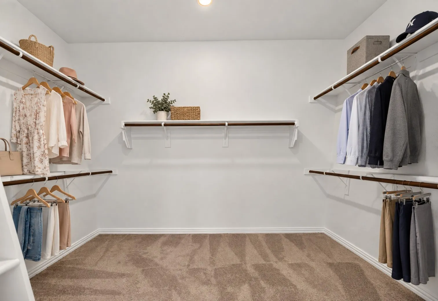 Walk-in closet featuring white shelving and wood-finish hanging rods