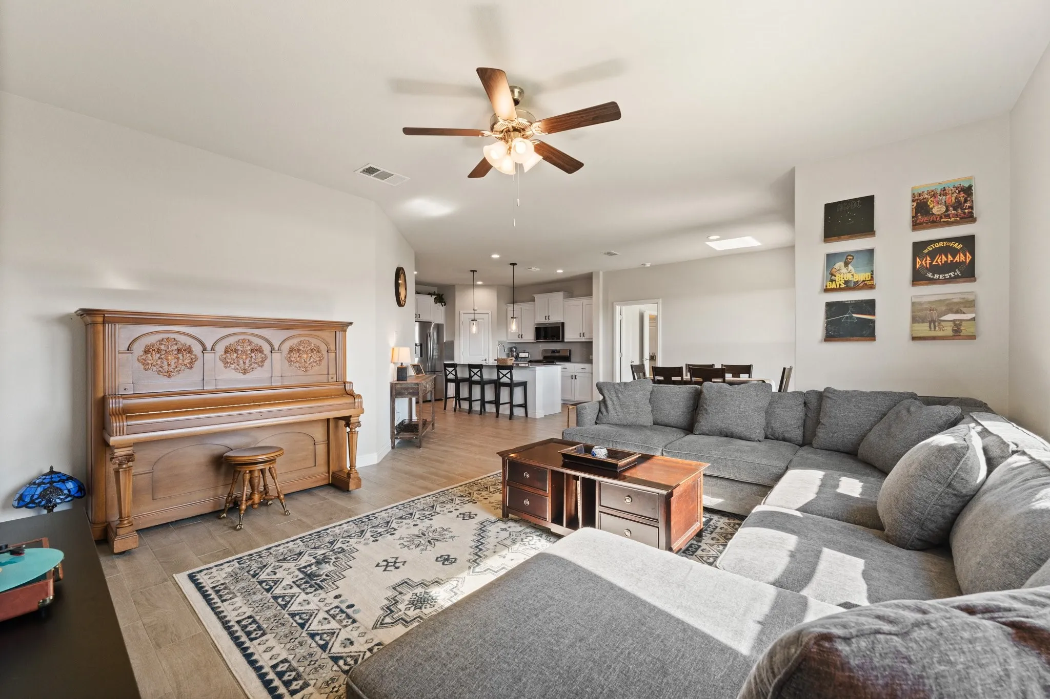 Open-concept living space featuring wood-finish flooring, a ceiling fan, and a skylight
