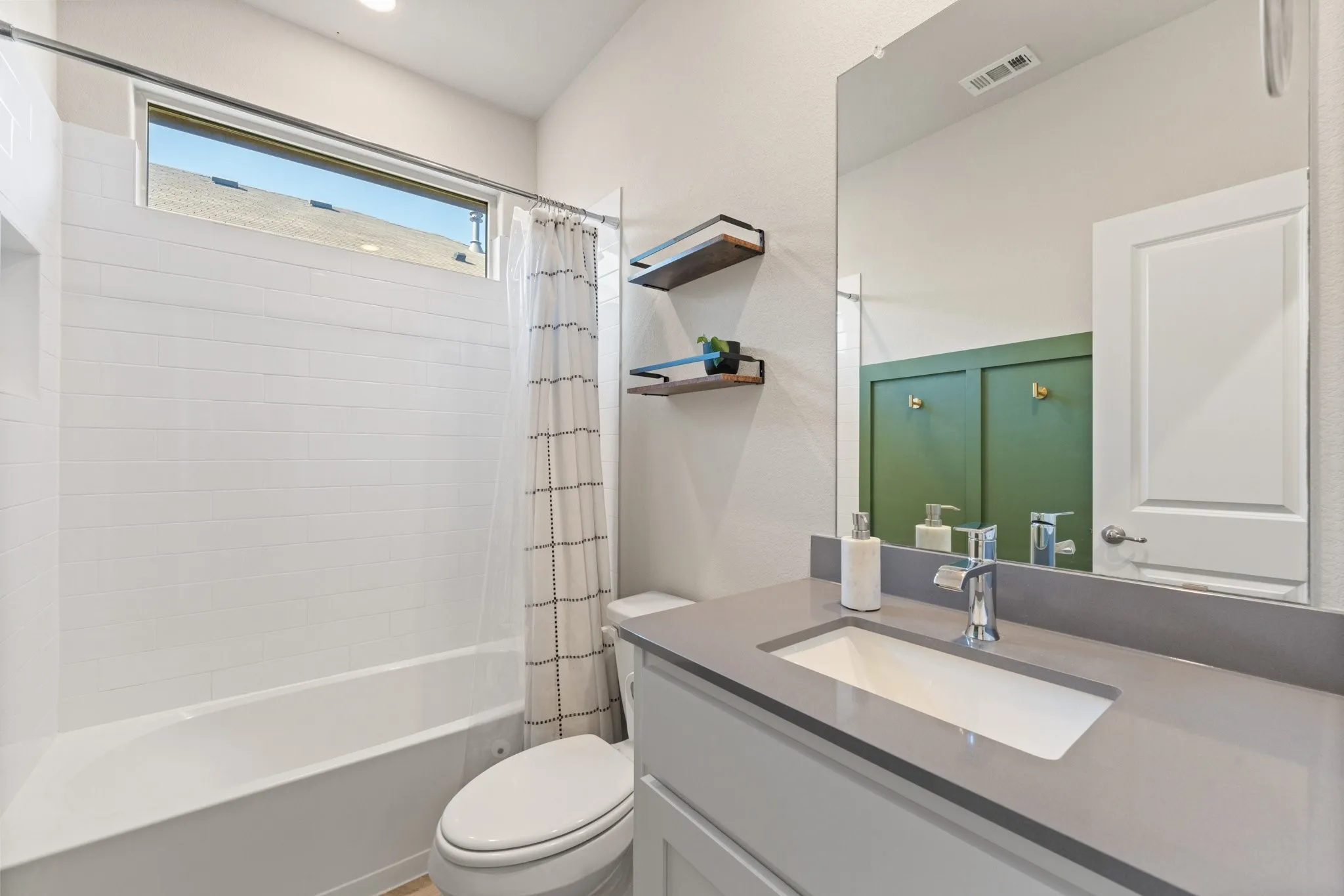 Bathtub with white subway tile surround and high transom window