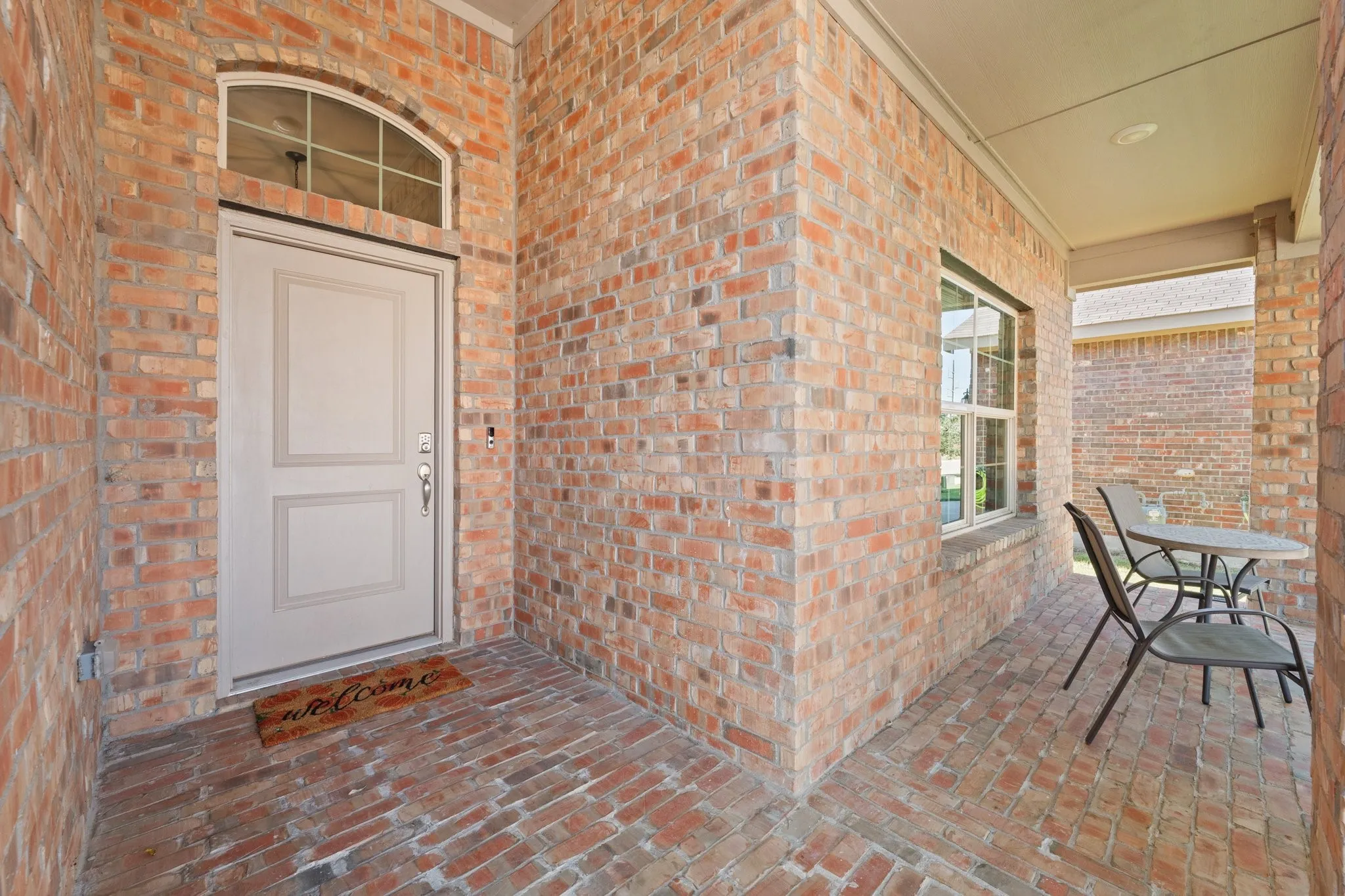 Brick exterior with a covered porch, arched transom window, and a paneled entry door