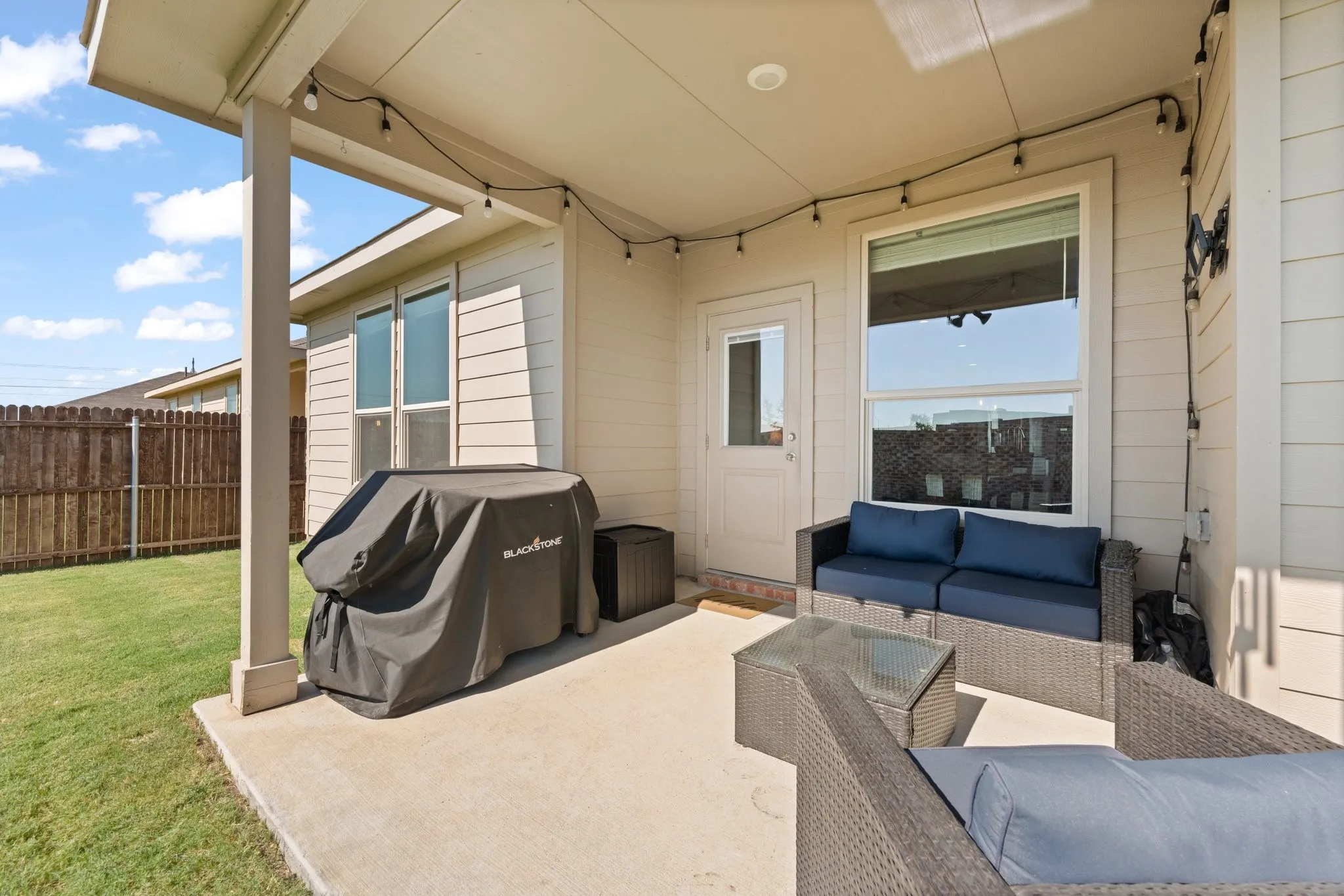 Covered patio with string lighting, concrete flooring, and direct exterior access