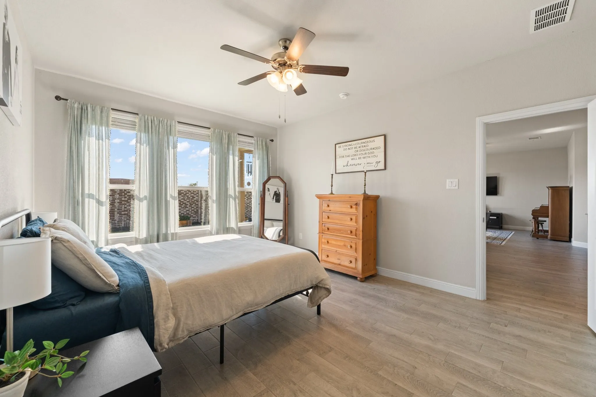 Wood-finish flooring throughout, light-toned wall paint, and a ceiling fan with integrated lighting