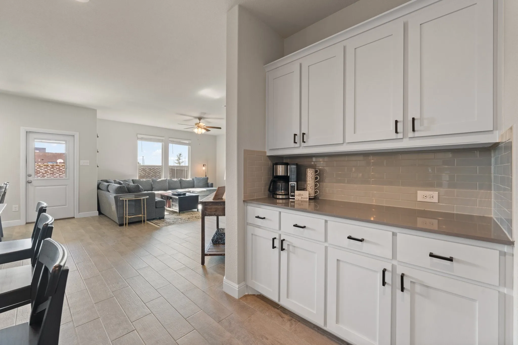 White shaker-style cabinetry with black hardware, solid surface countertops, and a subway tile backsplash