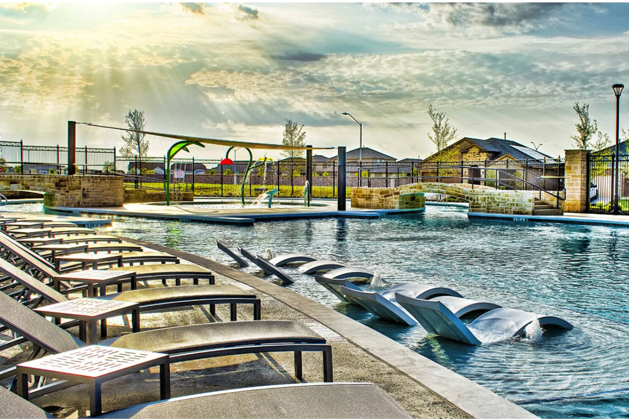 Expansive aquatic amenity featuring a large swimming pool, dedicated splash pad, and integrated in-pool lounge seating