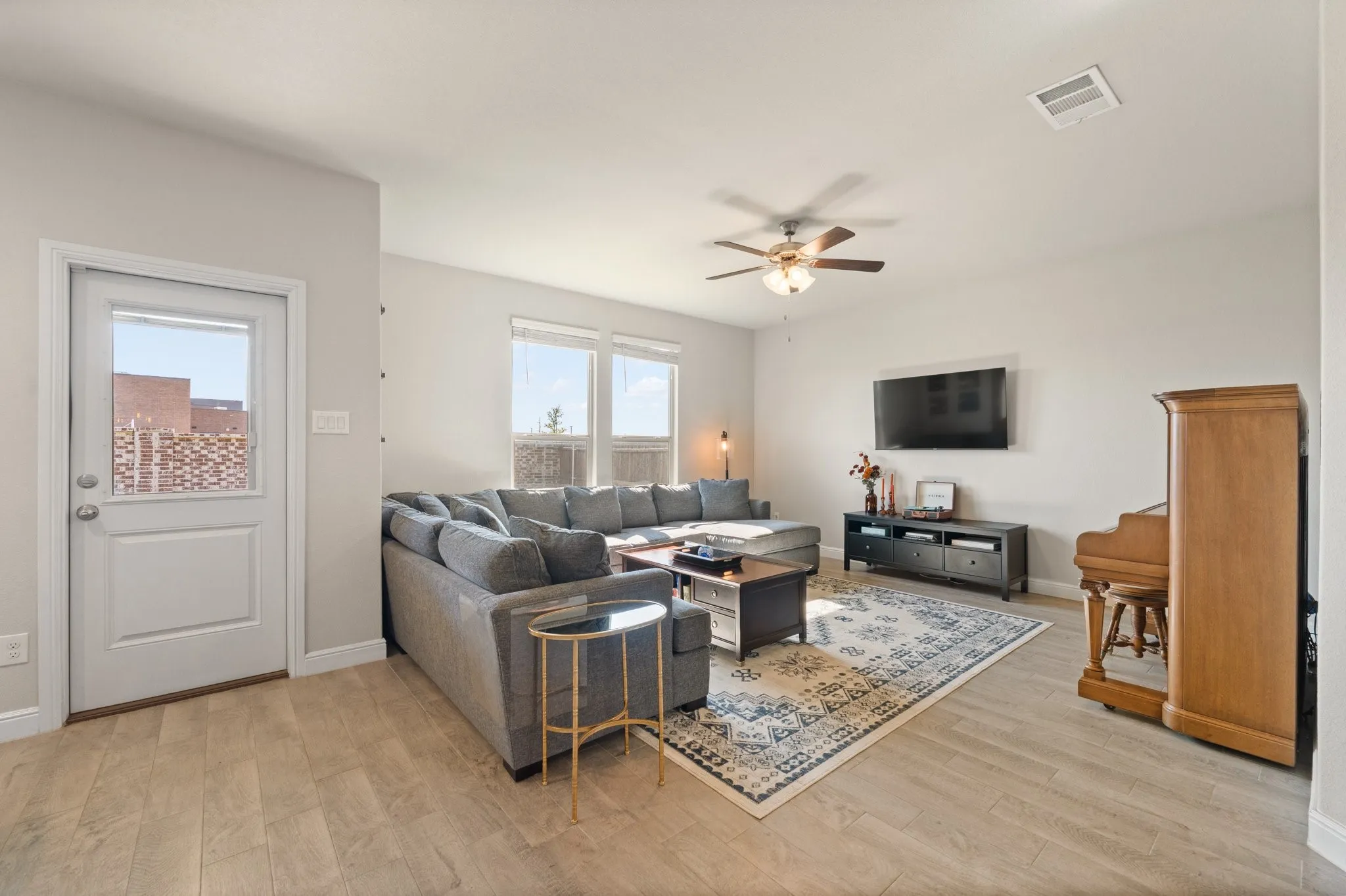 Spacious living area featuring wood-finish flooring, a ceiling fan, and multiple windows