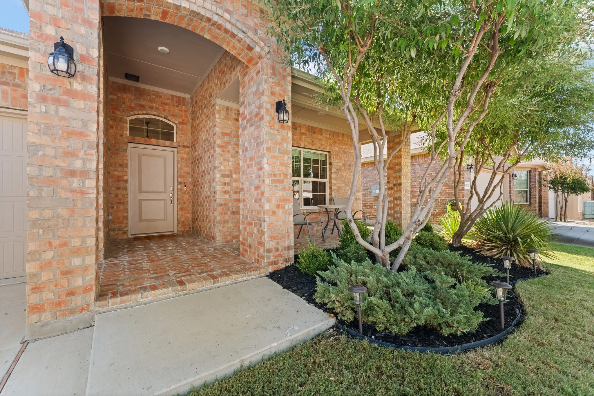 Brick exterior with an arched entry, covered porch, and mature landscaping