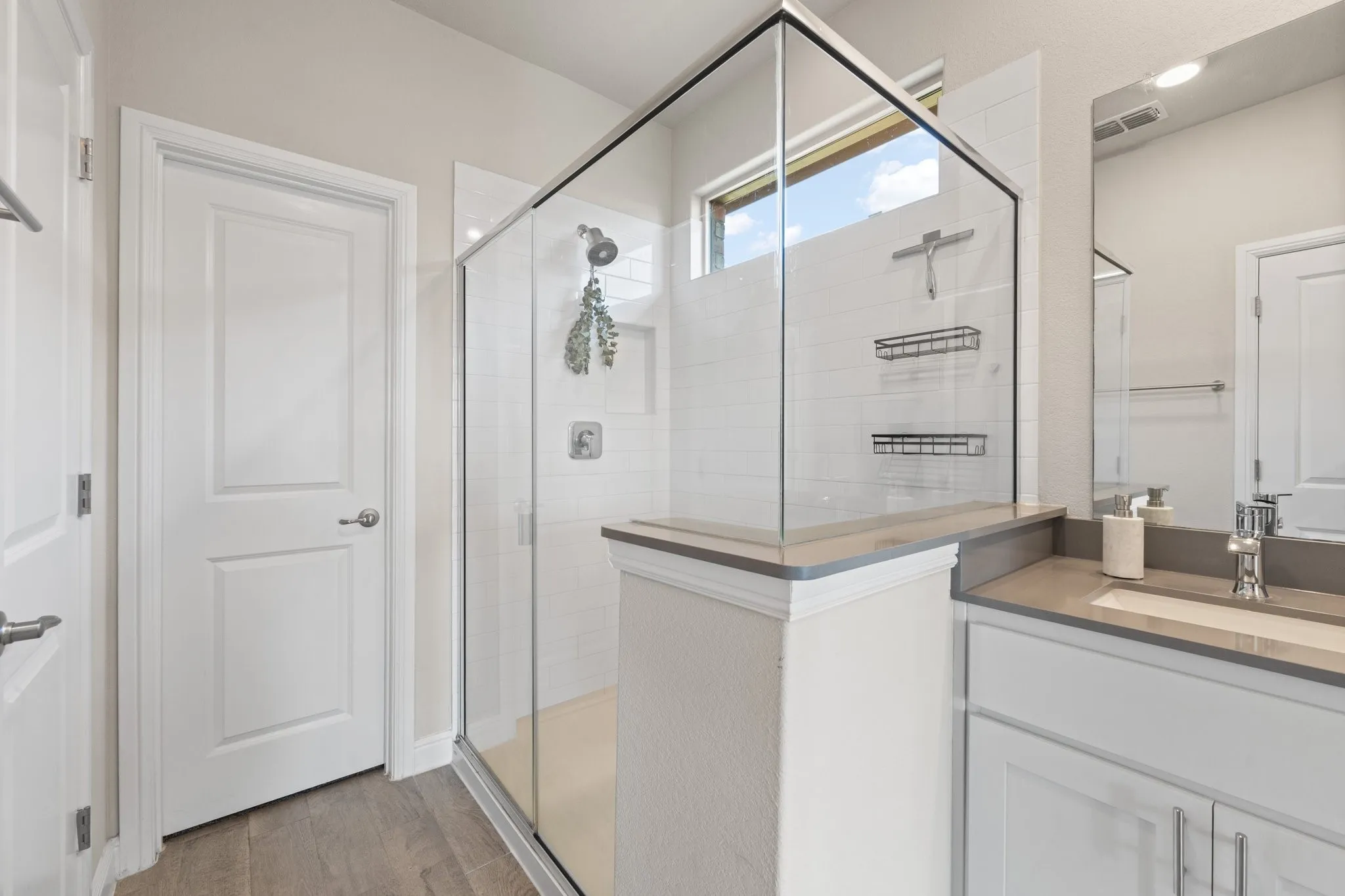 Glass-enclosed shower with subway tile surround, chrome fixtures, and transom window