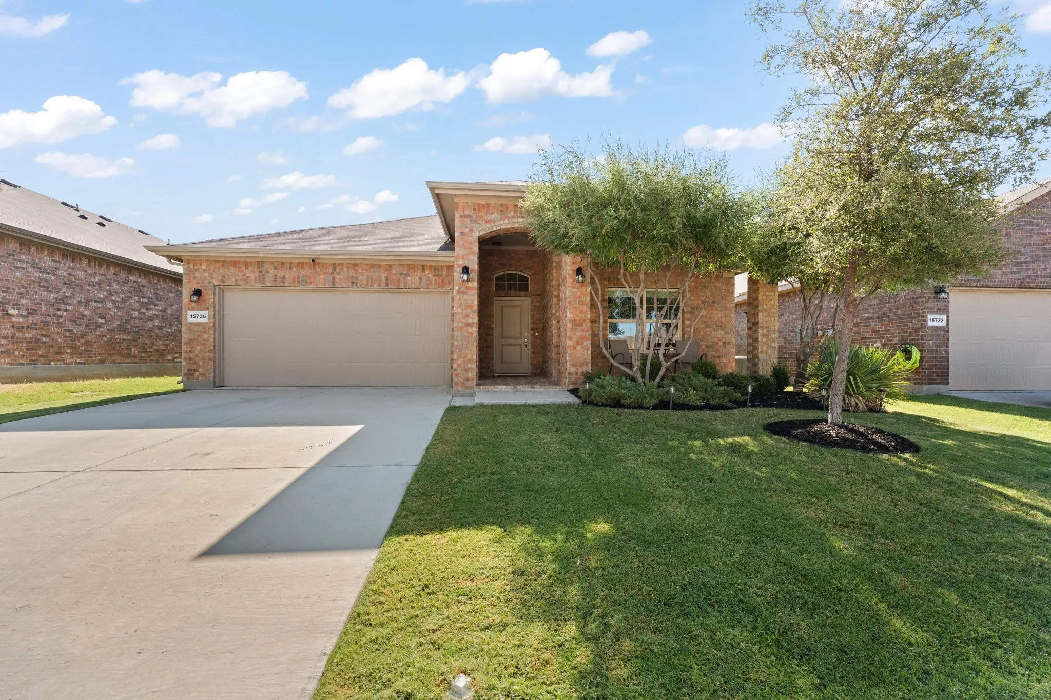 Brick exterior with an arched entry, attached two-car garage, and a concrete driveway
