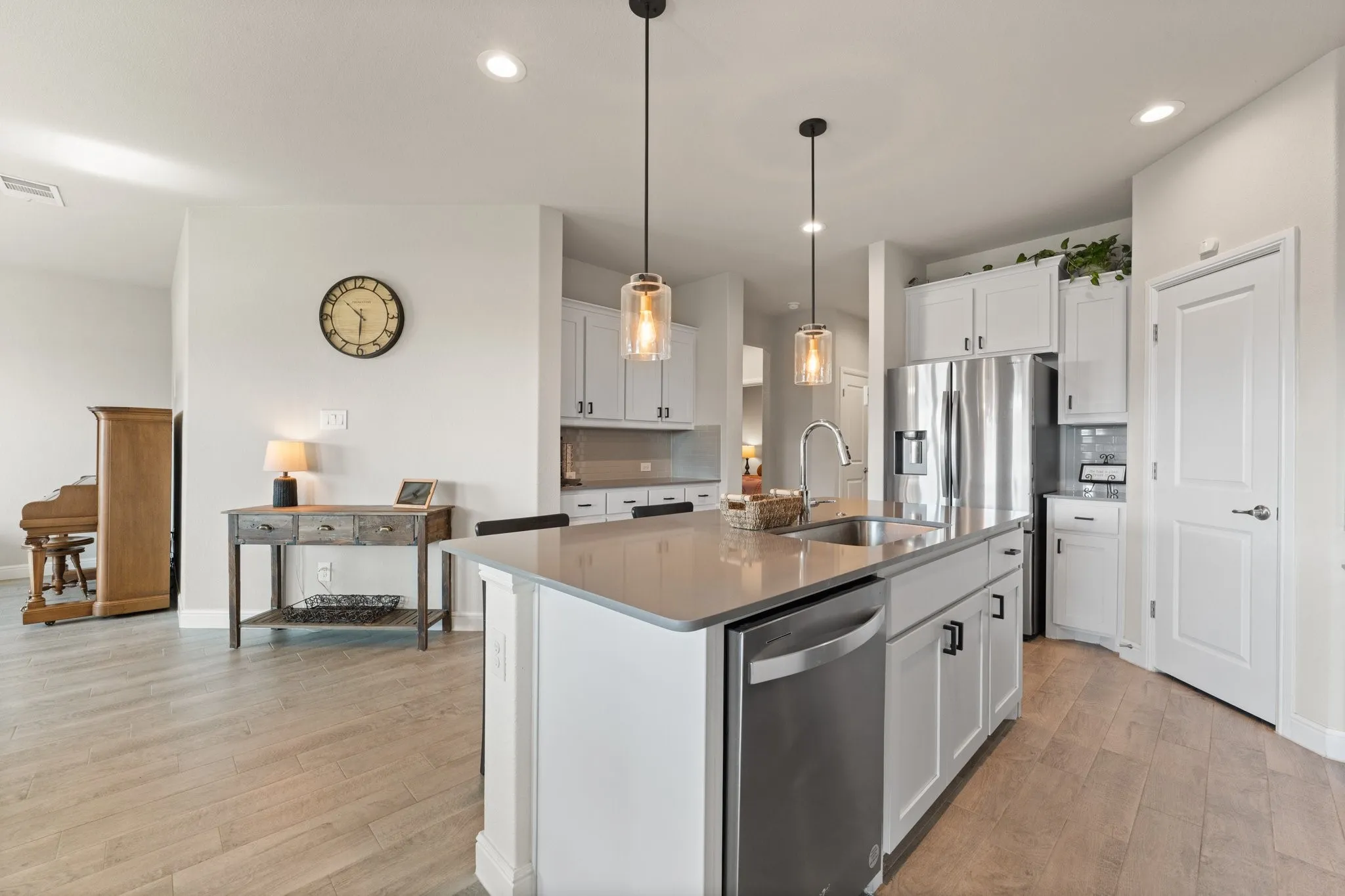 Kitchen island with integrated sink, stainless steel appliances, white cabinetry, and recessed lighting