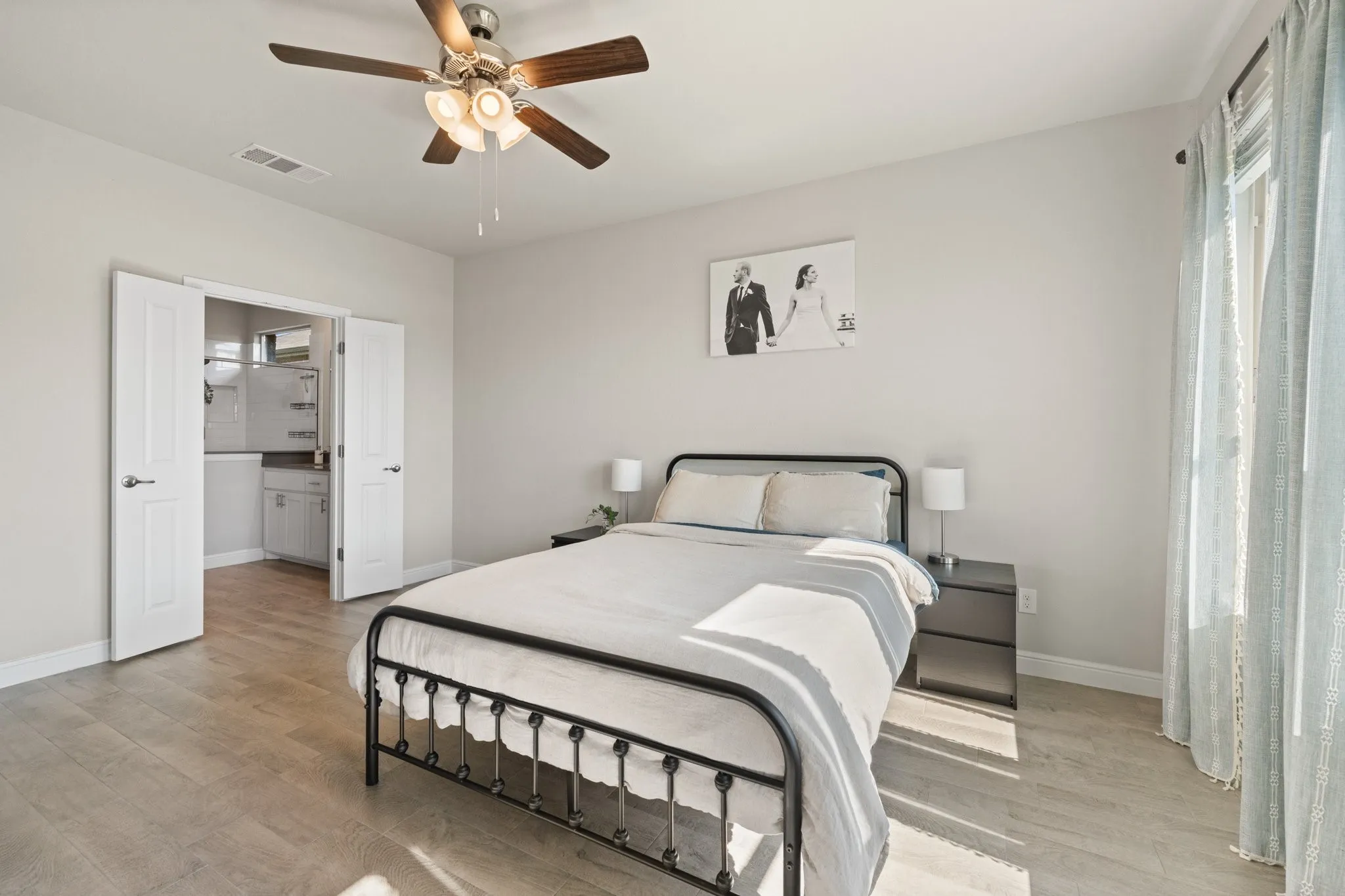 Wood-finish flooring throughout, light neutral wall tones, and a ceiling fan with integrated lighting