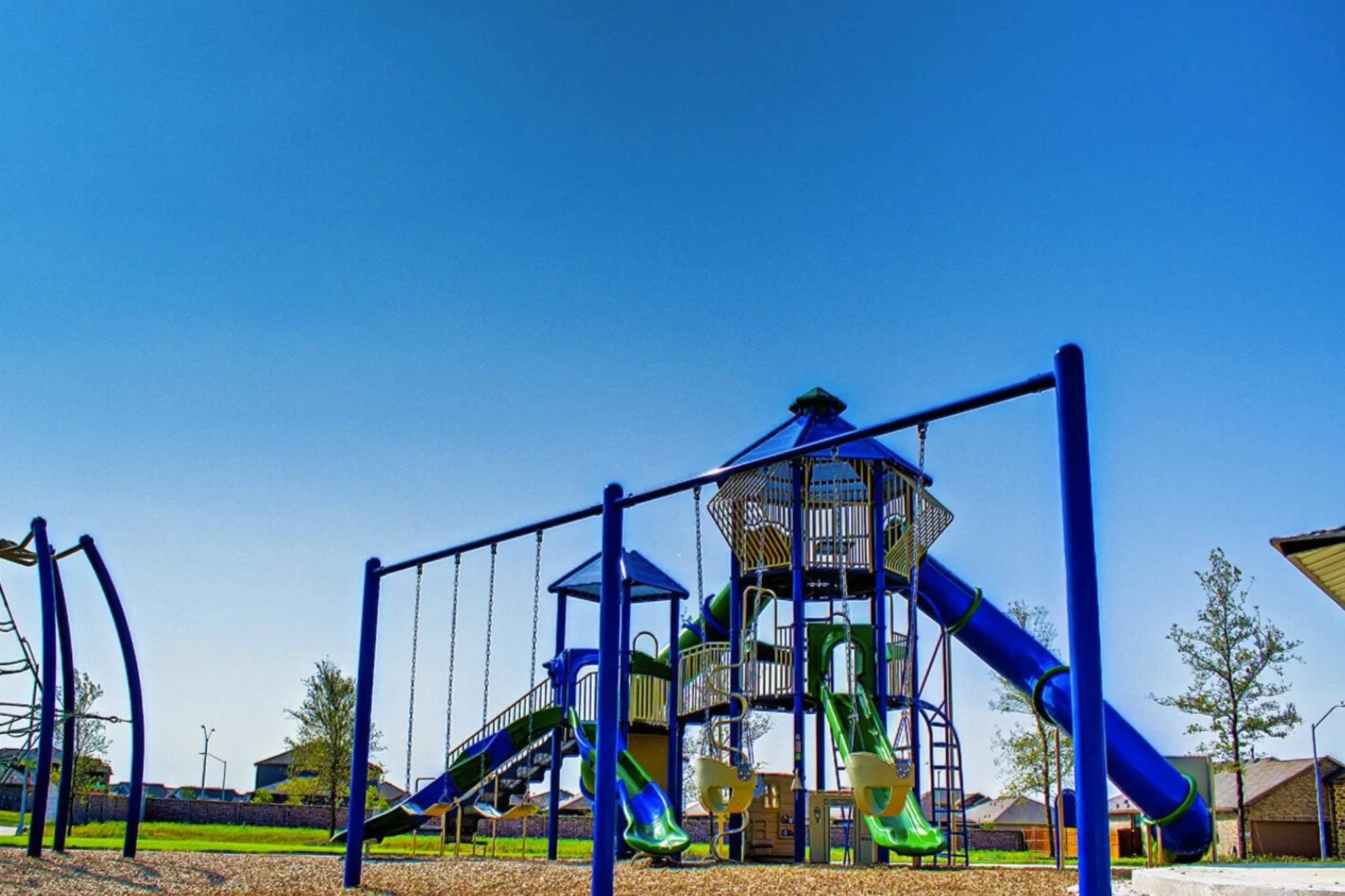 Outdoor play structure featuring multiple slides, swing sets, and climbing elements