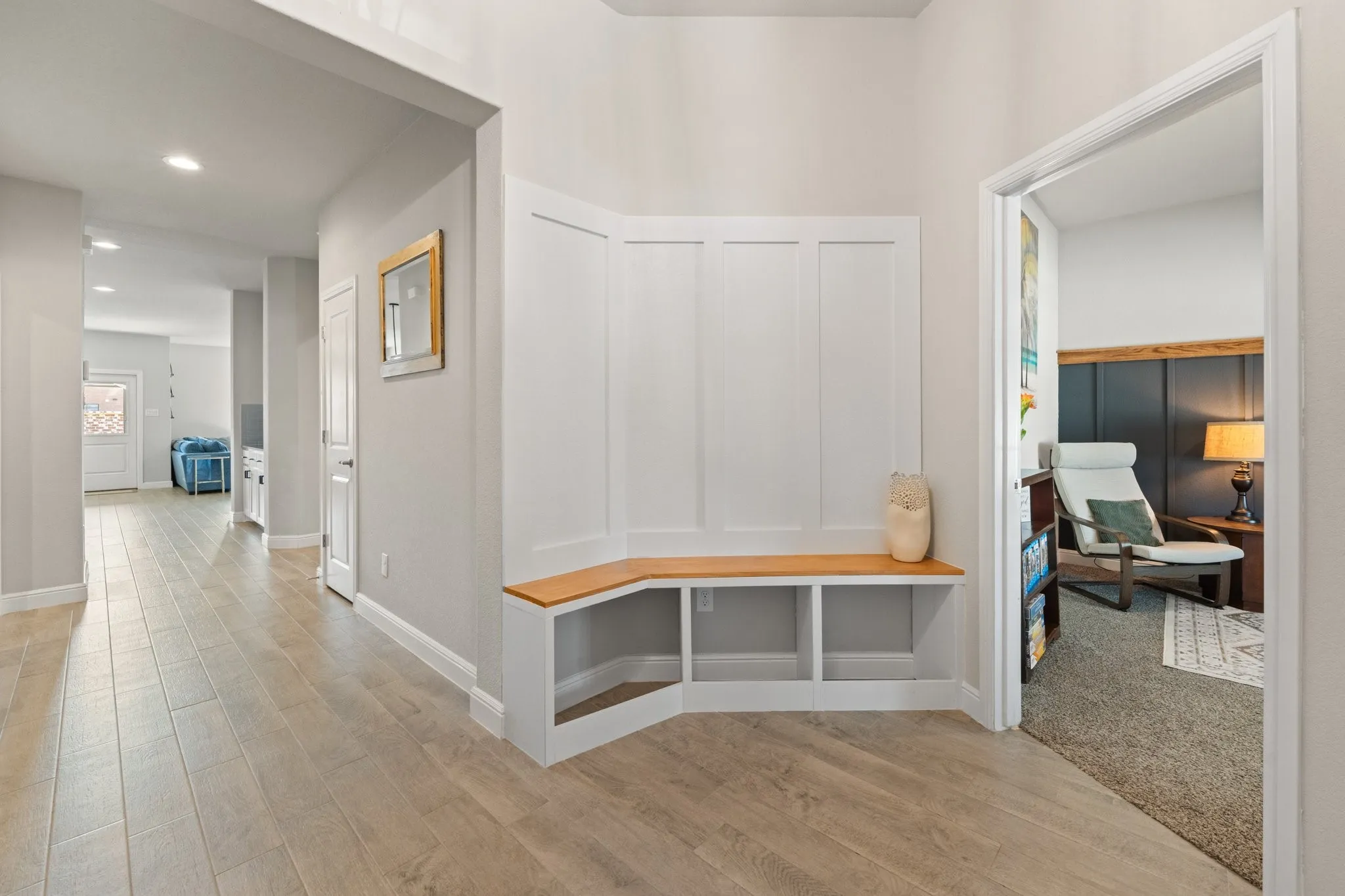 Integrated built-in bench with storage, wood-finish flooring, recessed lighting, and a white paneled accent wall