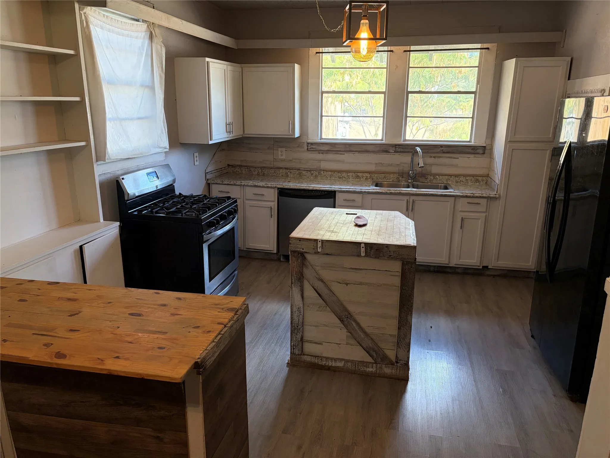 Kitchen featuring wood-finish flooring, white cabinetry, a gas range, stainless steel sink with a gooseneck faucet, and light-toned countertops