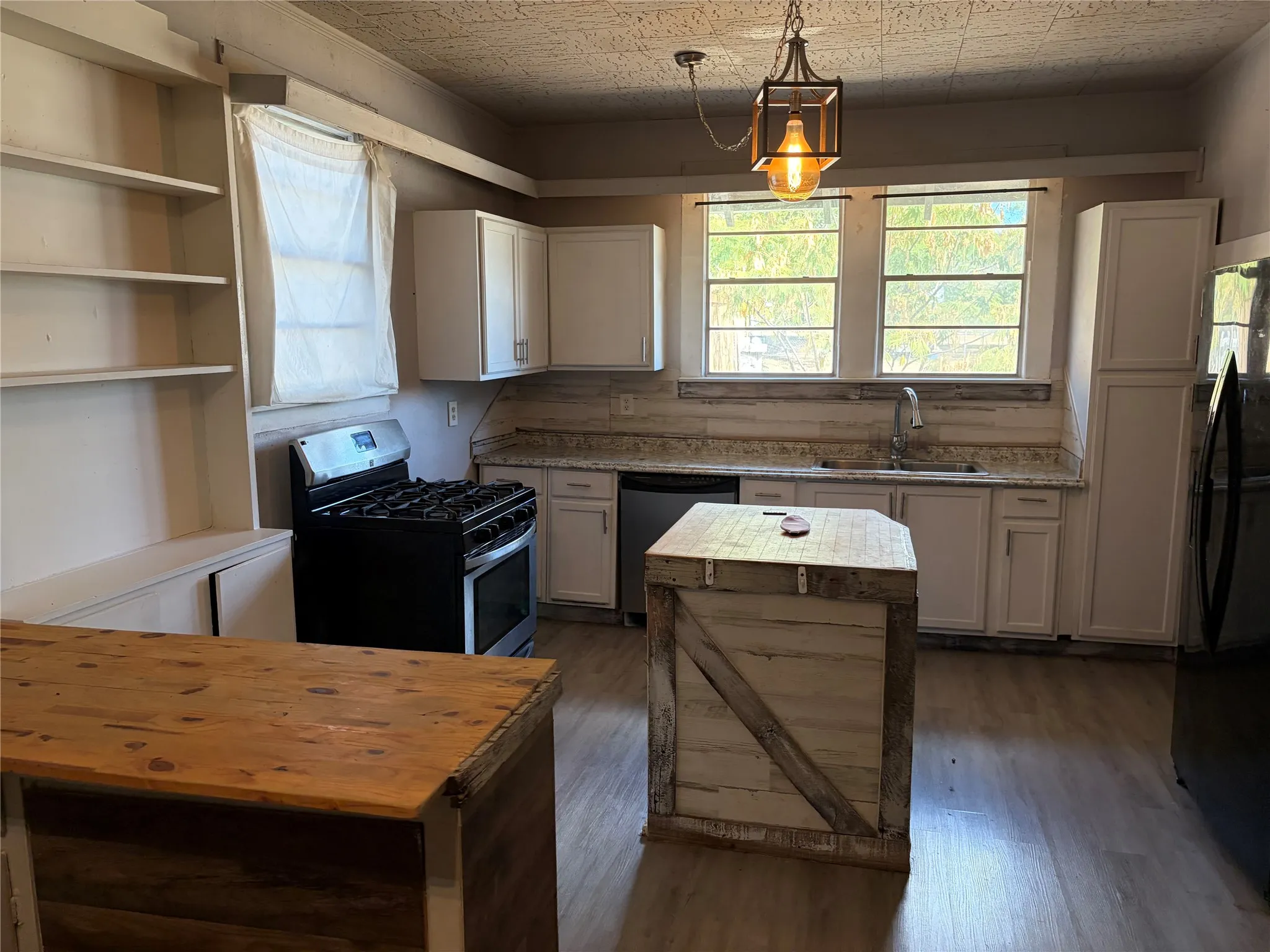 Kitchen featuring light wood-finish flooring, white cabinetry, a built-in shelving unit, a gas range, and a freestanding island
