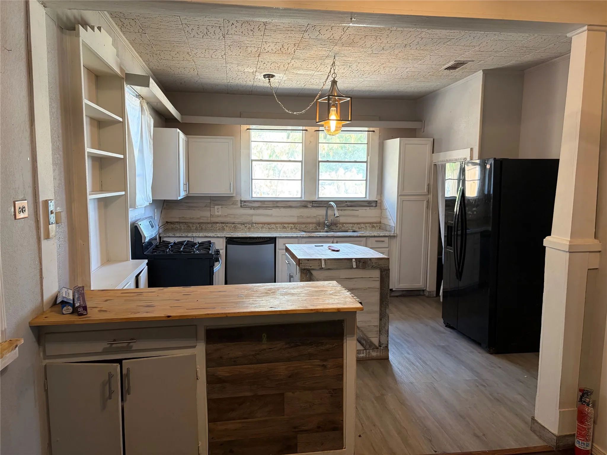 Kitchen featuring white cabinetry, built-in shelving, wood-finish flooring, and a central island with a wood-finish countertop
