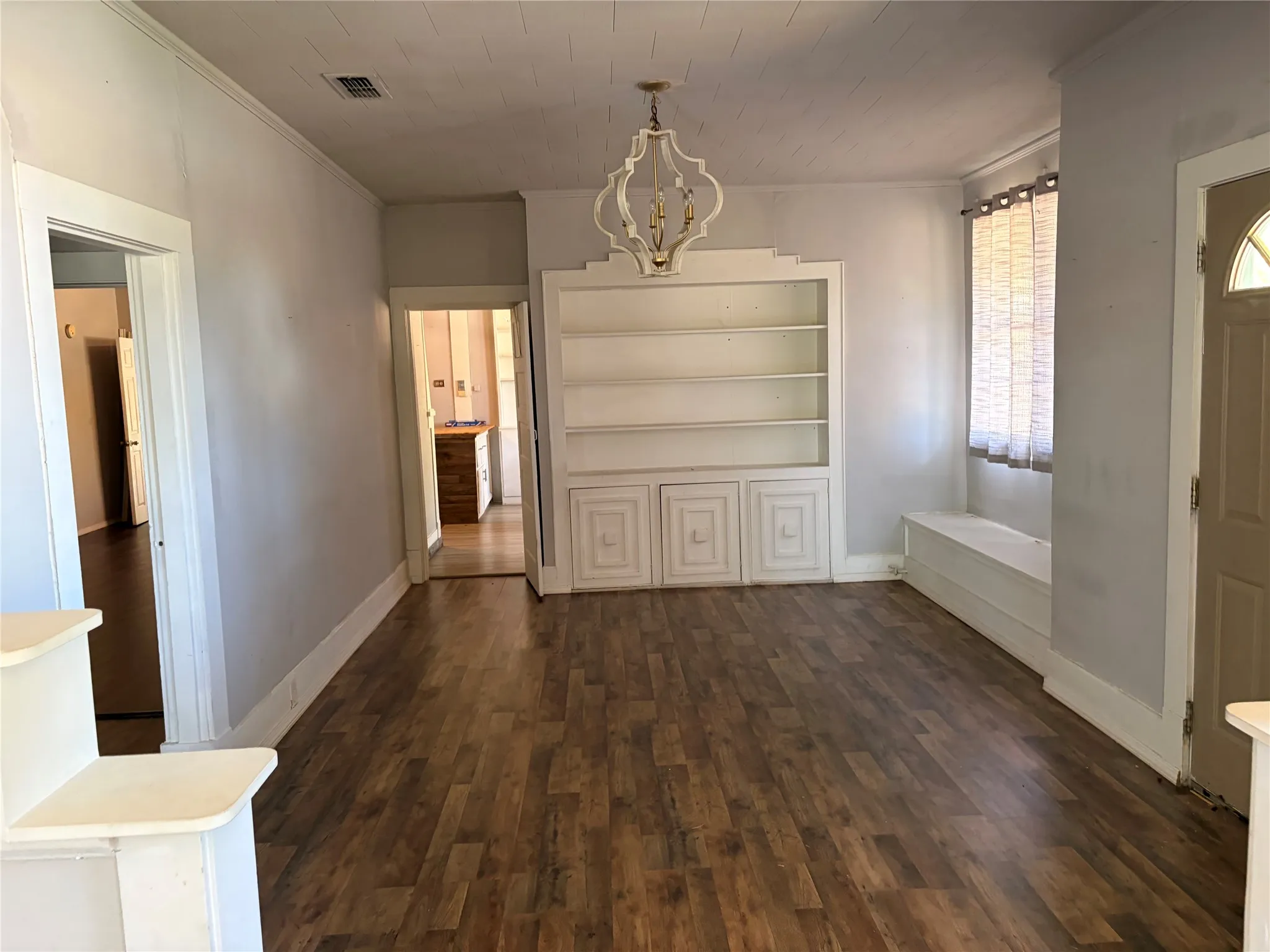 Wood-finish flooring throughout, integrated built-in shelving, decorative overhead lighting, and a built-in window bench
