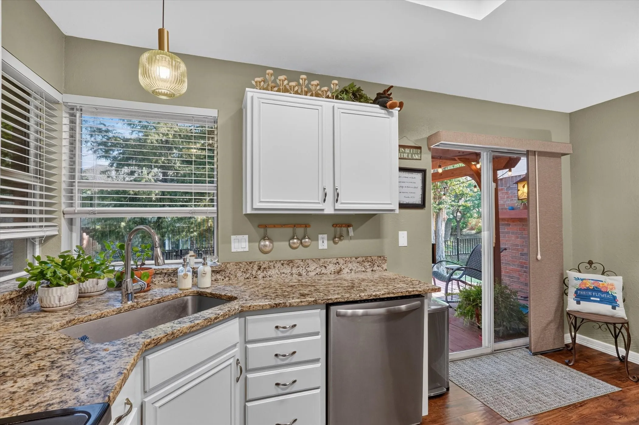 Kitchen featuring granite countertops, a stainless steel sink with a pull-down faucet, white cabinetry, and stainless steel appliances