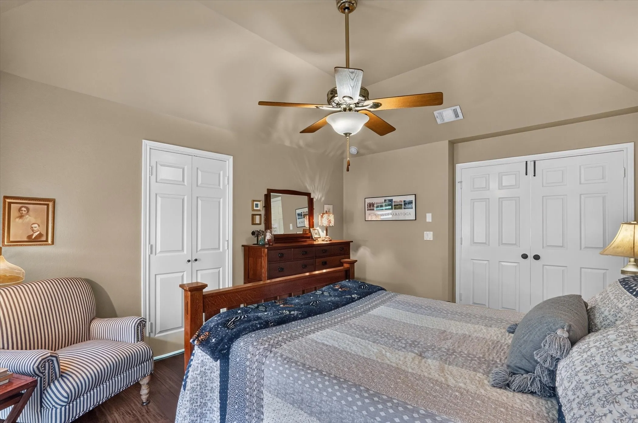 Vaulted ceiling with a ceiling fan, wood-finish flooring, and white paneled doors