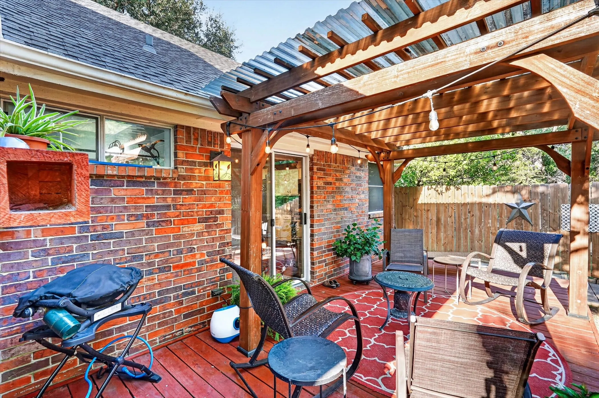 Brick exterior with a built-in planter, wood deck, and a wood pergola featuring a translucent panel roof