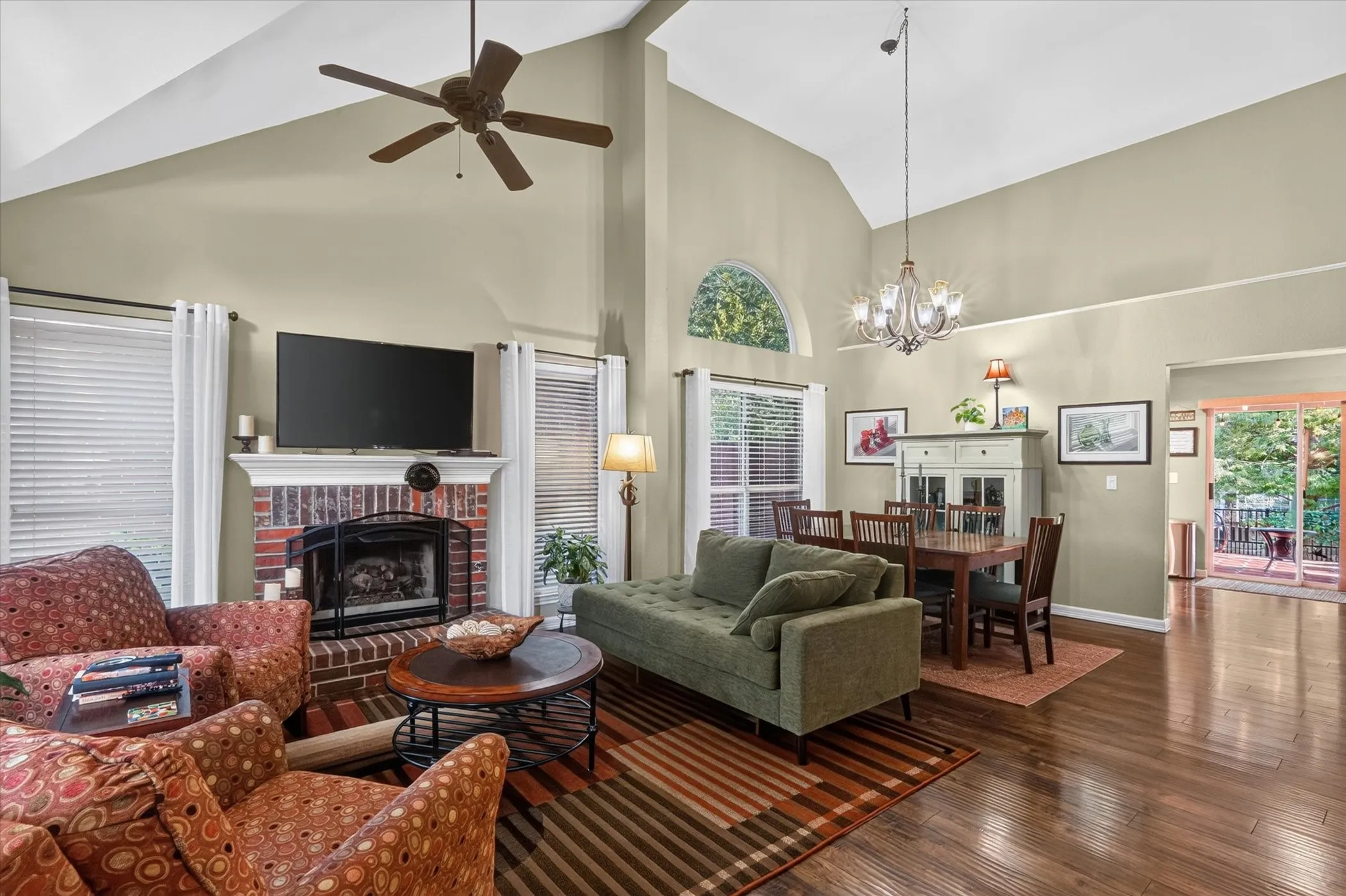 Vaulted ceilings, a brick fireplace with a mantel, wood-finish flooring.