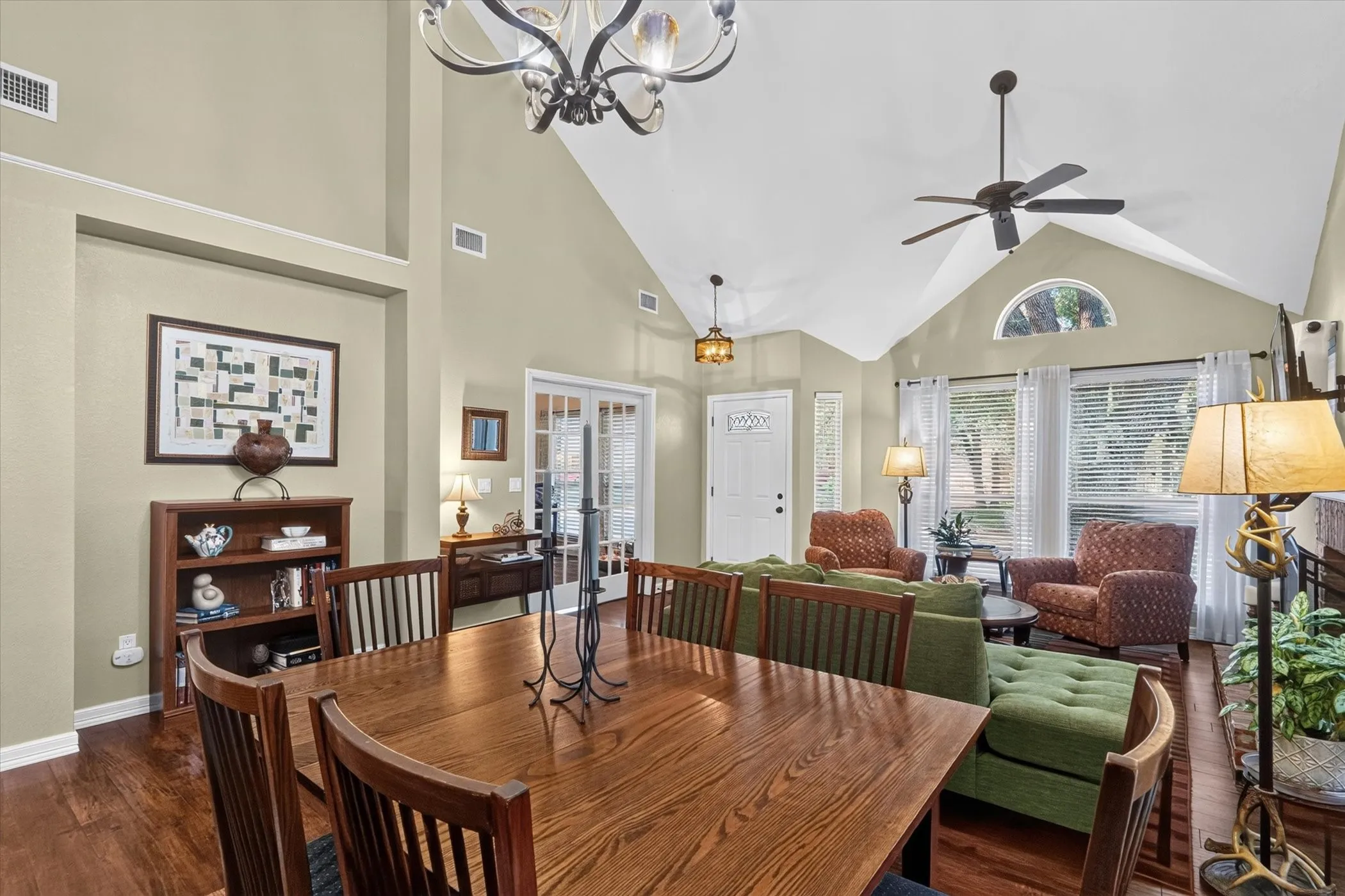 Vaulted ceilings with exposed beams, wood-finish flooring, and a decorative chandelier
