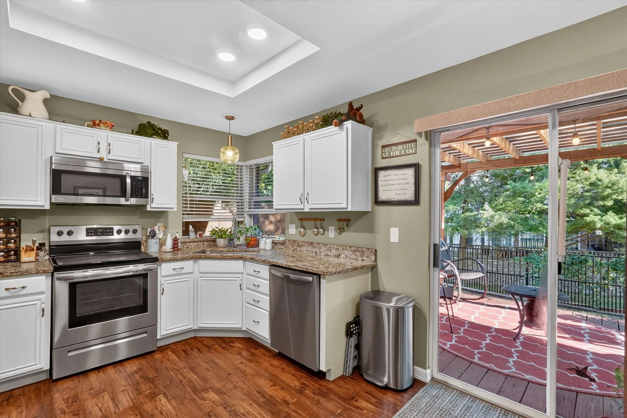 Kitchen featuring white cabinetry, stainless steel appliances, and wood-finish flooring