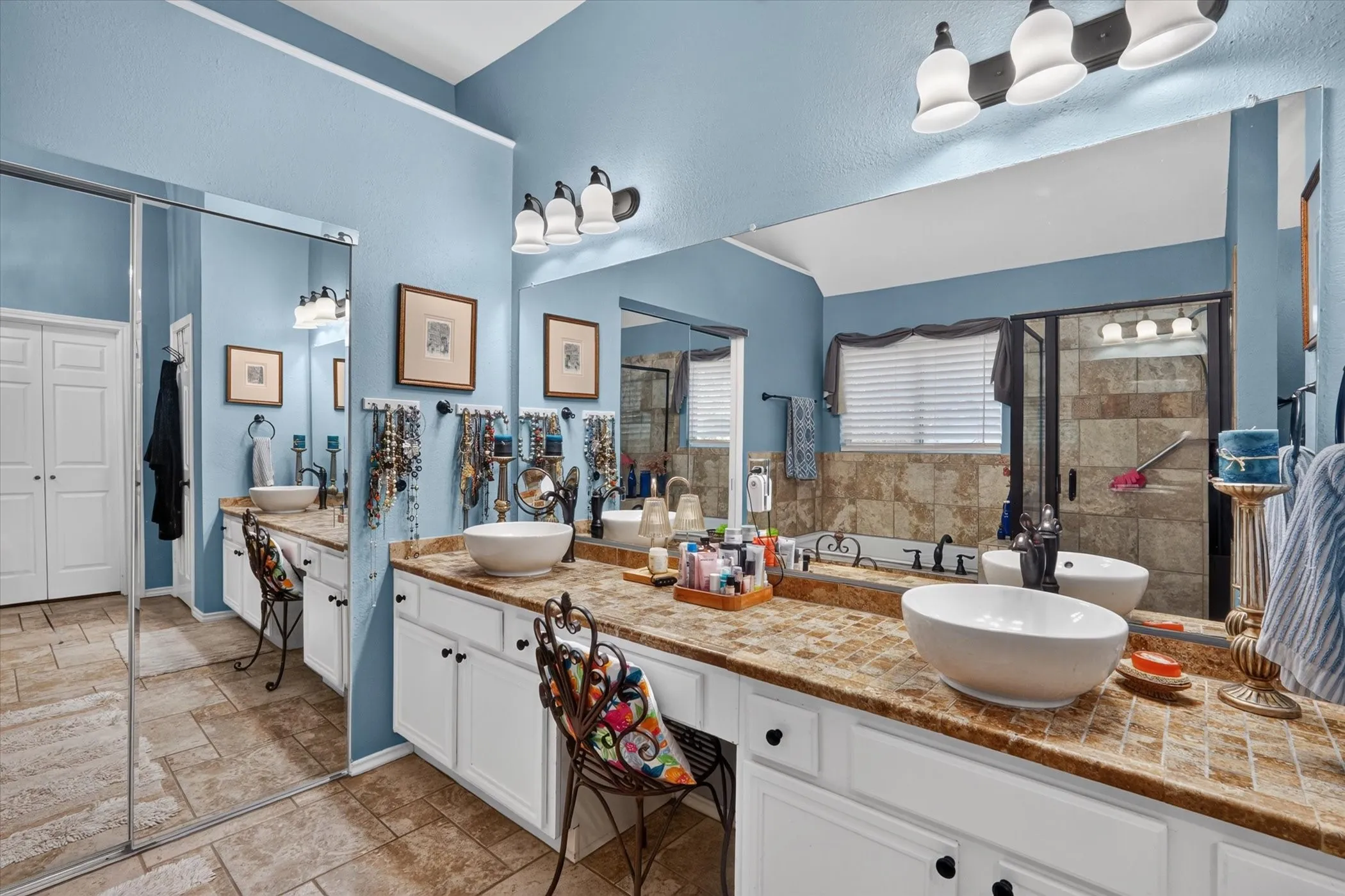 Double vanity with vessel sinks, white cabinetry, and stone-look countertops