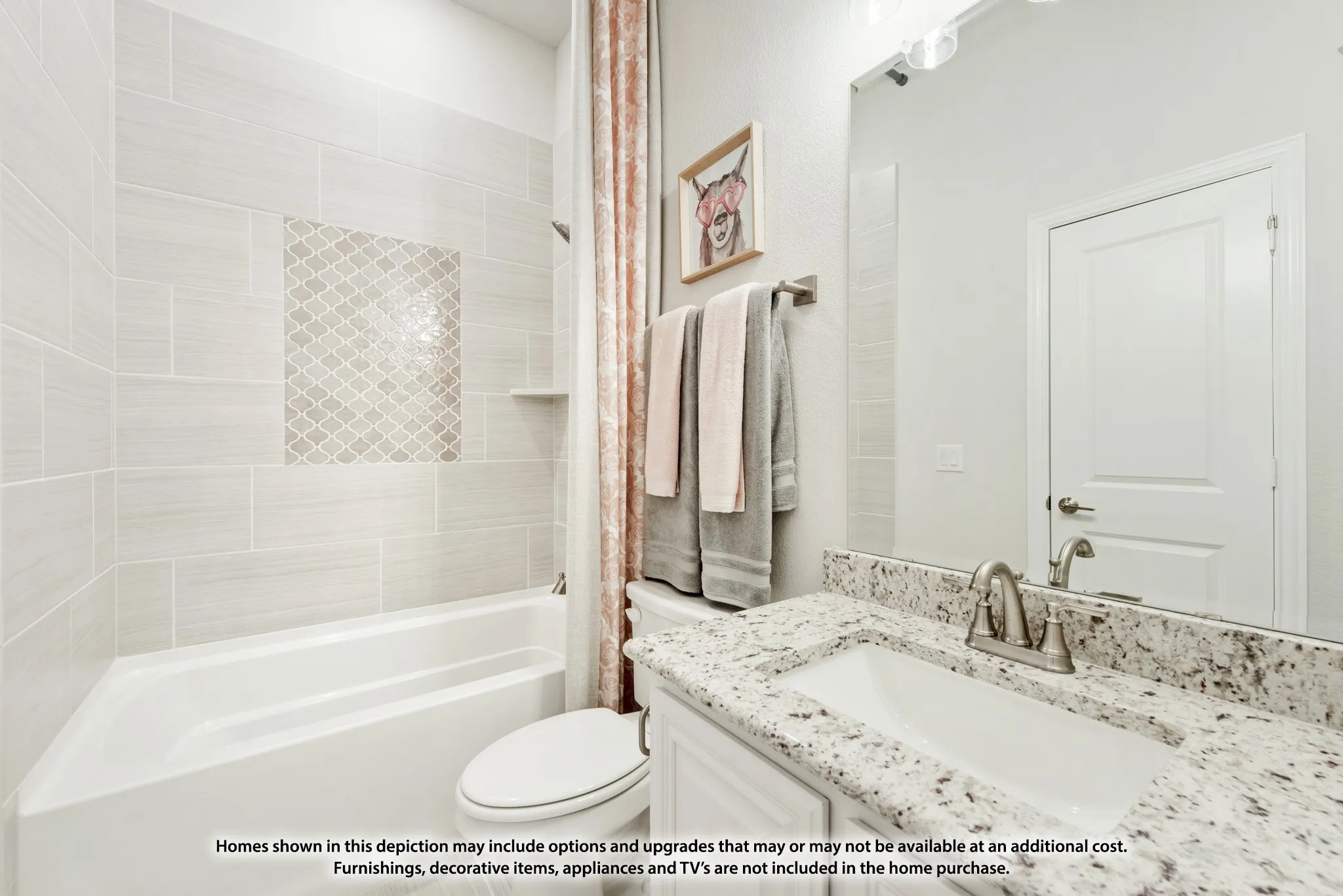 Bathtub with tiled surround, decorative mosaic tile accent, built-in shelving, vanity with stone countertop, and an integrated sink