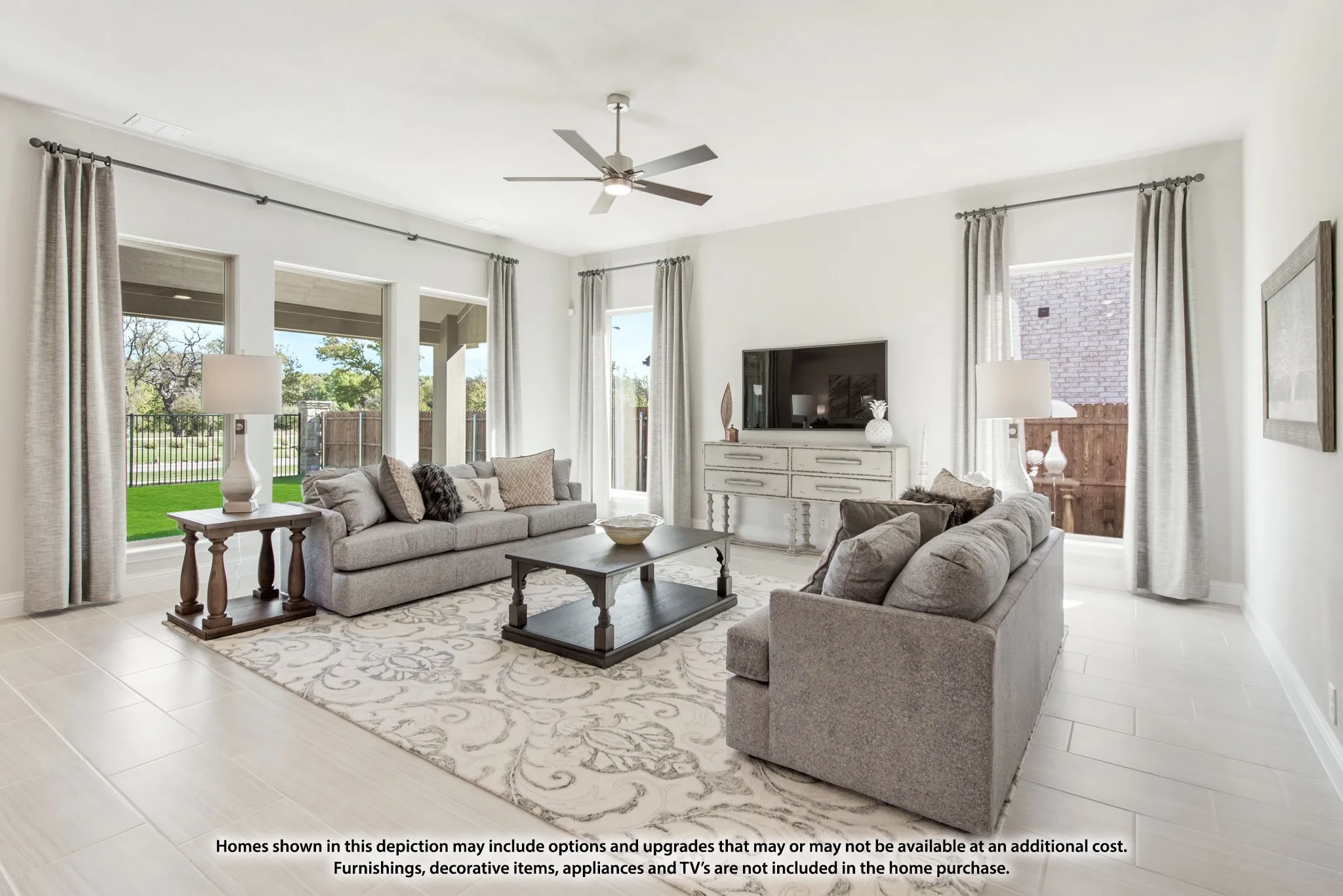 High ceilings with a ceiling fan, multiple large windows, light-toned wood-finish flooring, and a built-in console