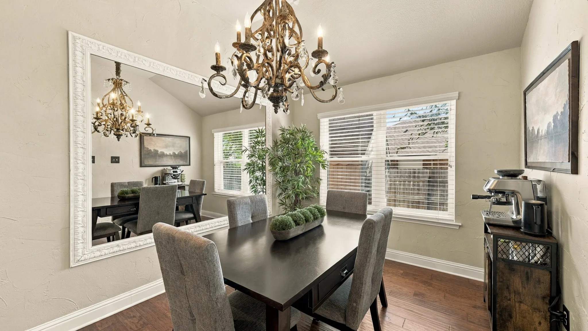 Vaulted ceiling, engineered wood flooring, two windows with blinds, and a built-in chandelier