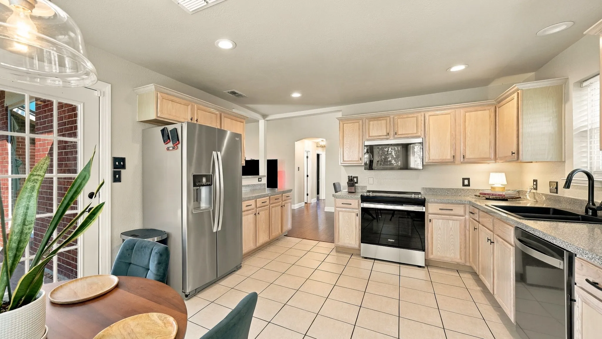 Kitchen featuring stainless steel appliances, light wood-finish cabinetry, tile flooring, and light-toned countertops