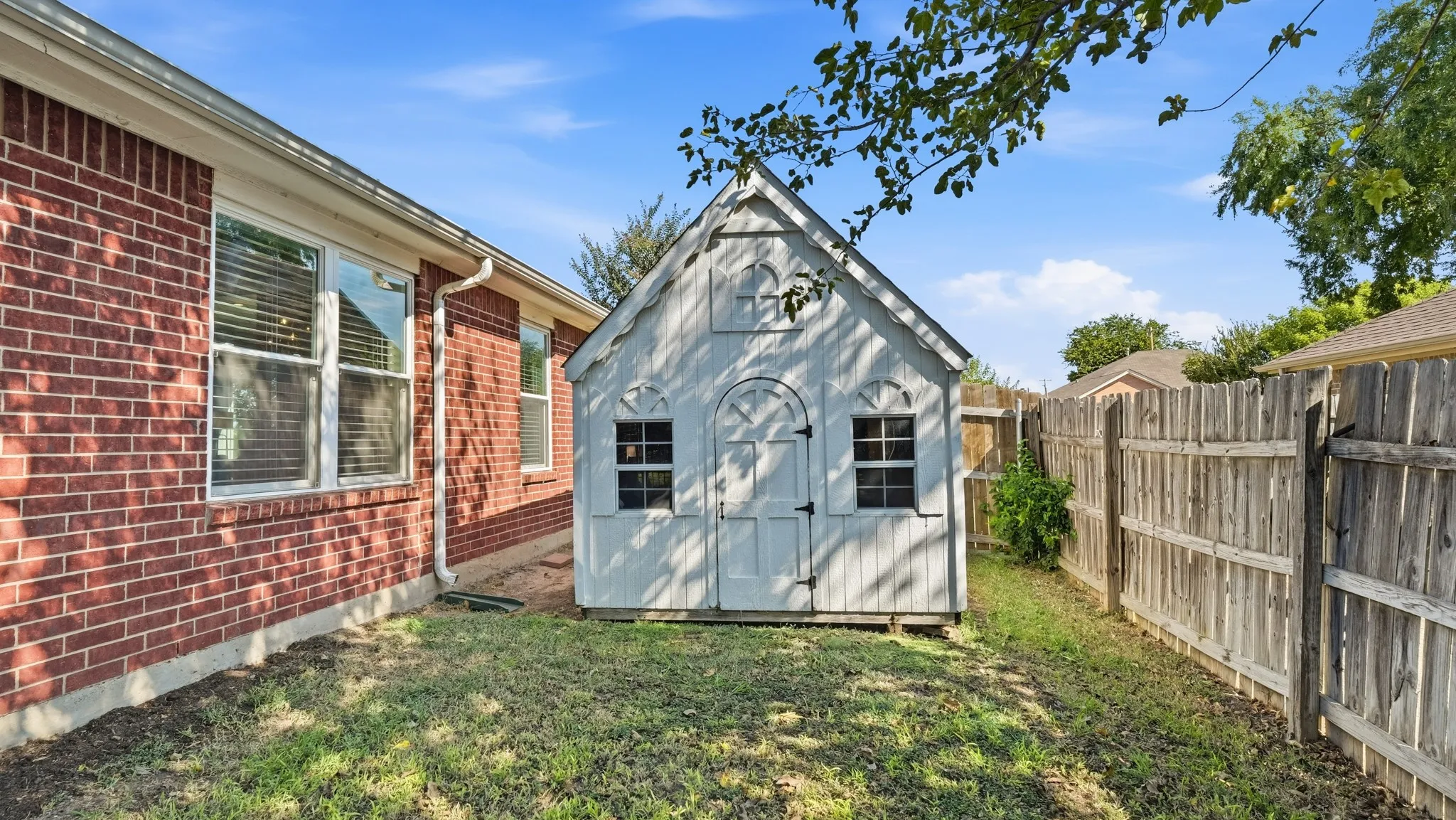 Red brick exterior with white trim windows and a functional storage shed