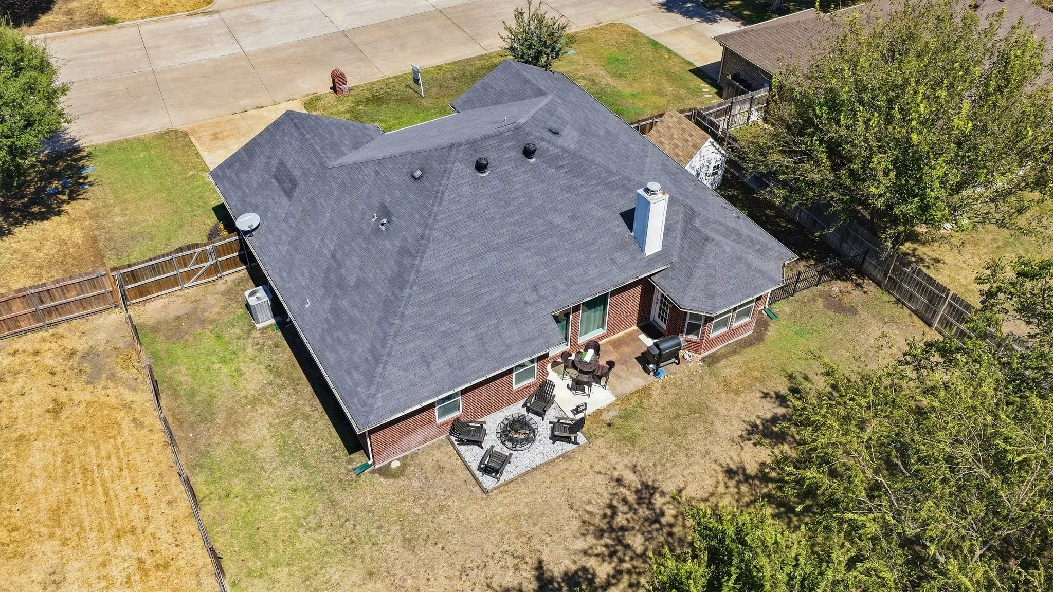 Exterior featuring a dark shingle roof, chimney, and a concrete patio
