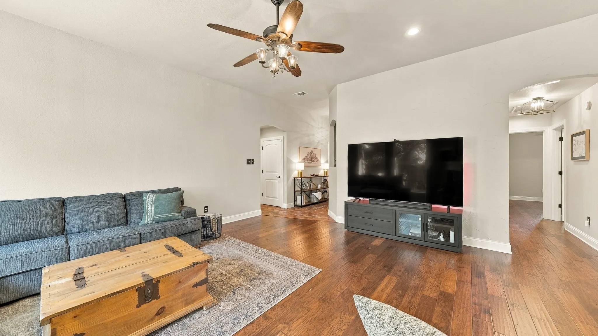 Wood-finish flooring throughout the room with light-toned walls and a ceiling fan