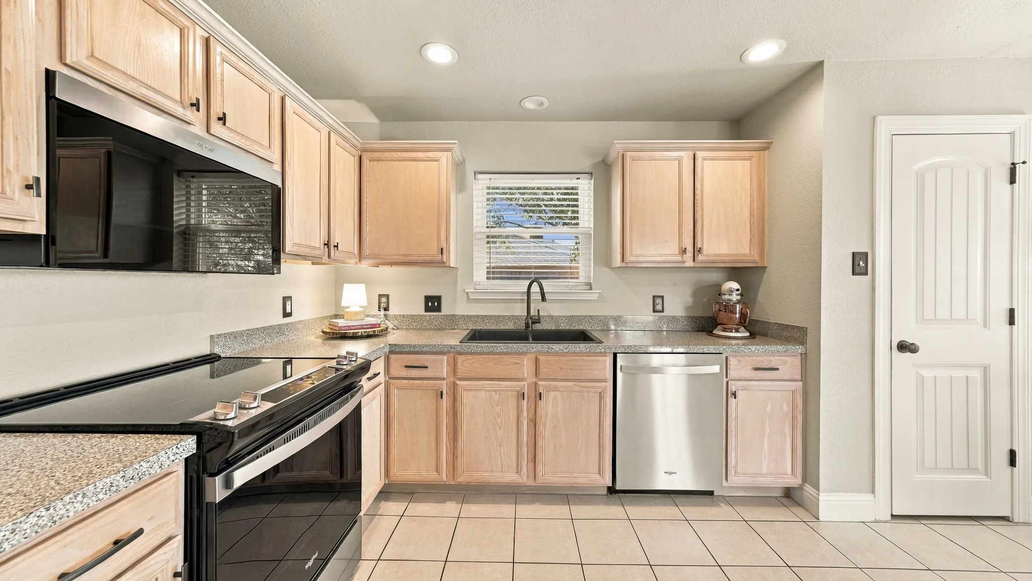 Kitchen featuring light wood-finish cabinetry, granite-style countertops, stainless steel appliances, and recessed lighting