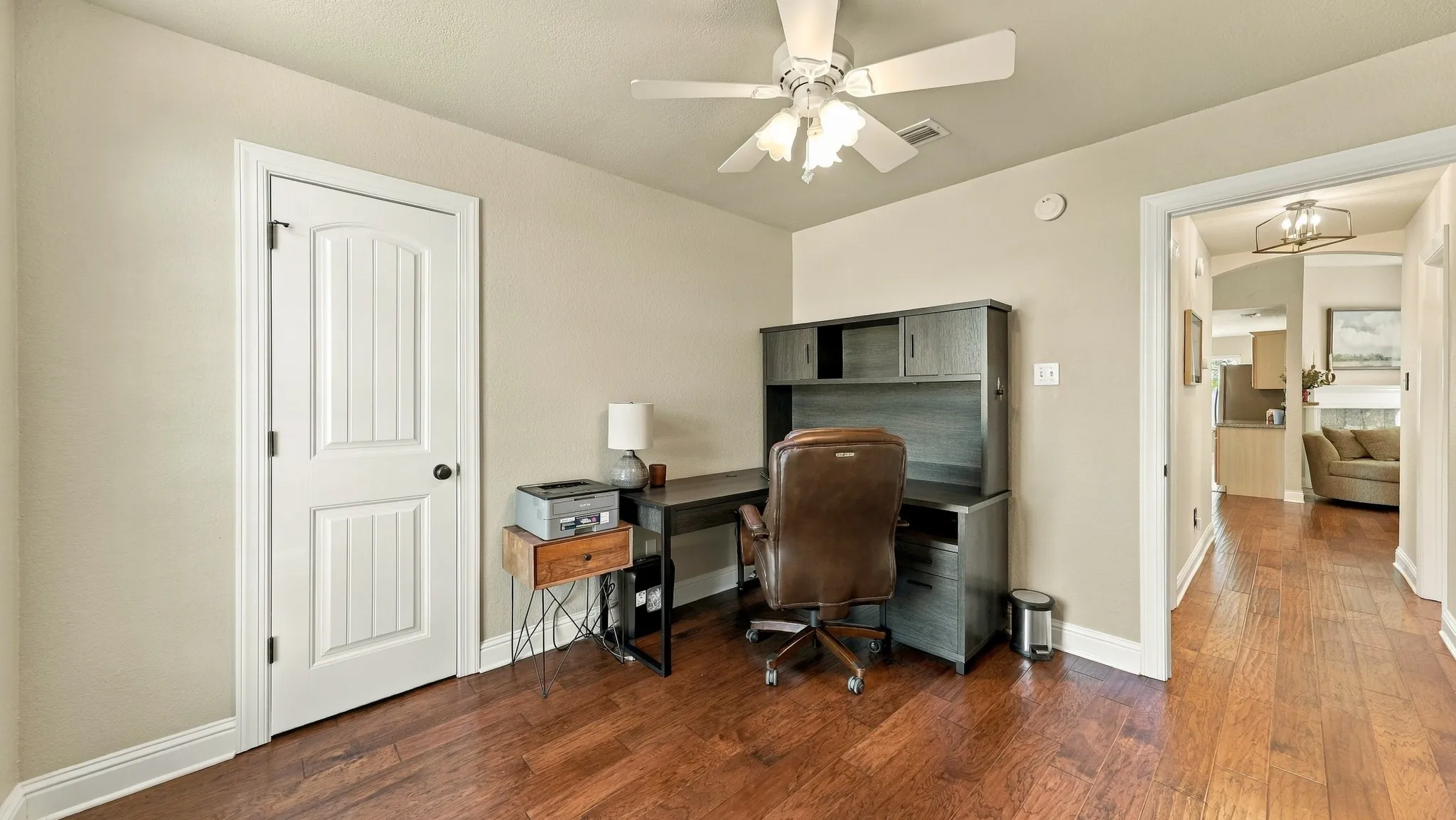 Hardwood flooring, ceiling fan, white paneled door, neutral wall color, recessed lighting