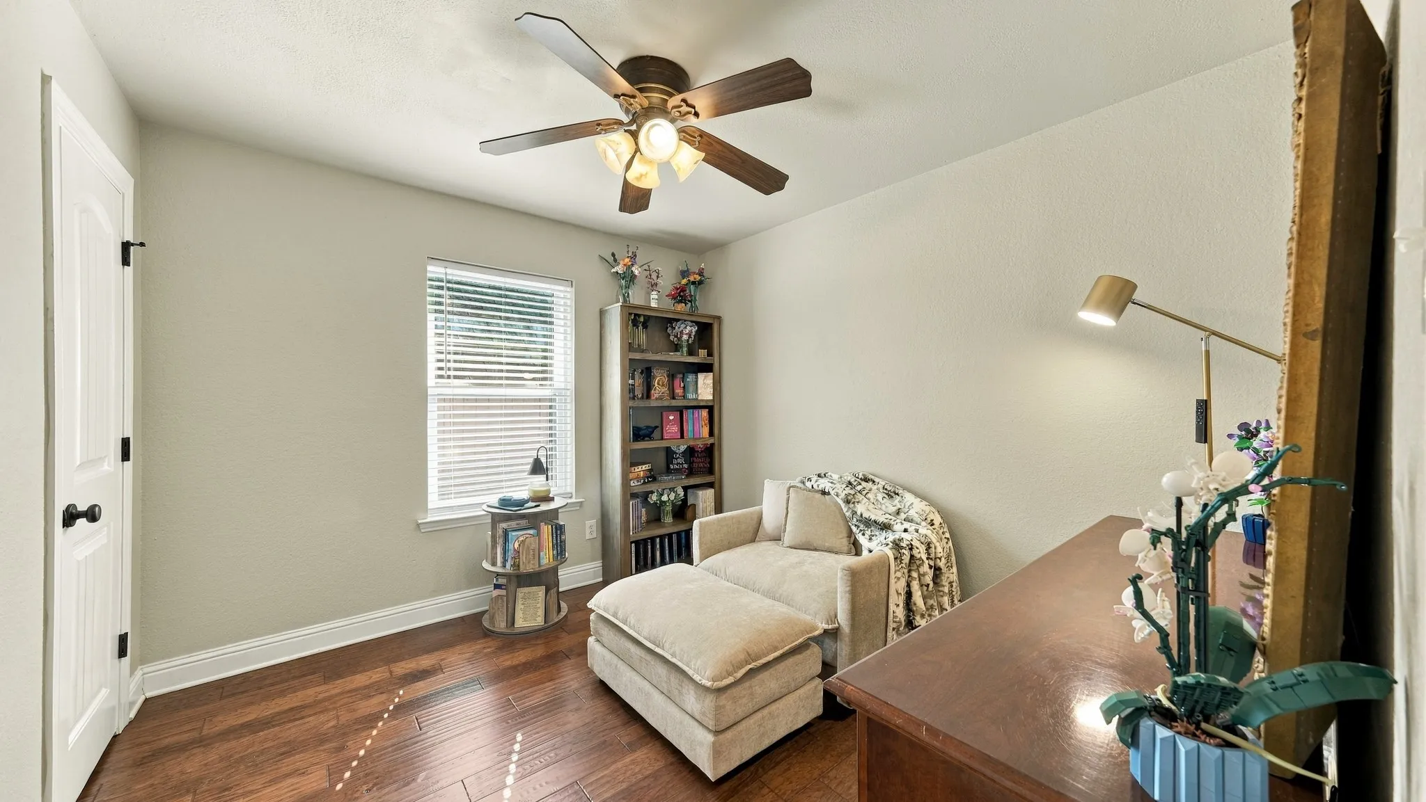 Wood-finish flooring with a ceiling fan light fixture and a single window with blinds